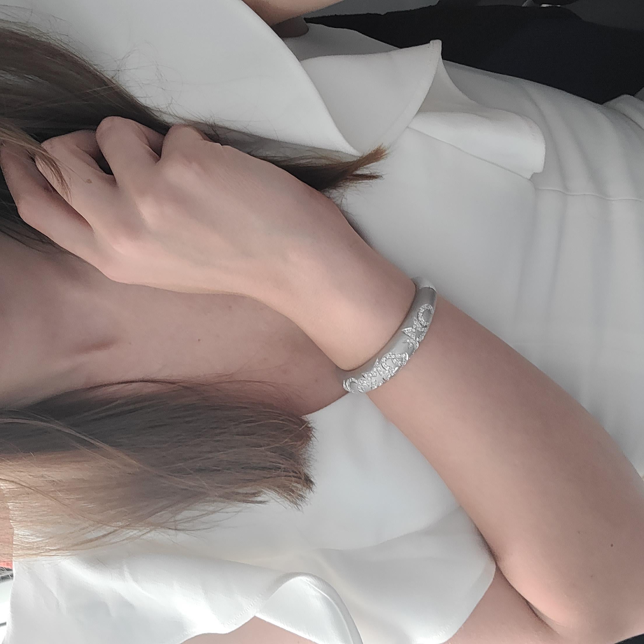 Bracelet bangle en diamant réalisé en or blanc 18k. Nature avec des cœurs, des étoiles et des croissants de lune entrelacés, sertis de 115 diamants ronds naturels de taille brillant montés en pavage dans un magnifique or blanc satiné. Poids total