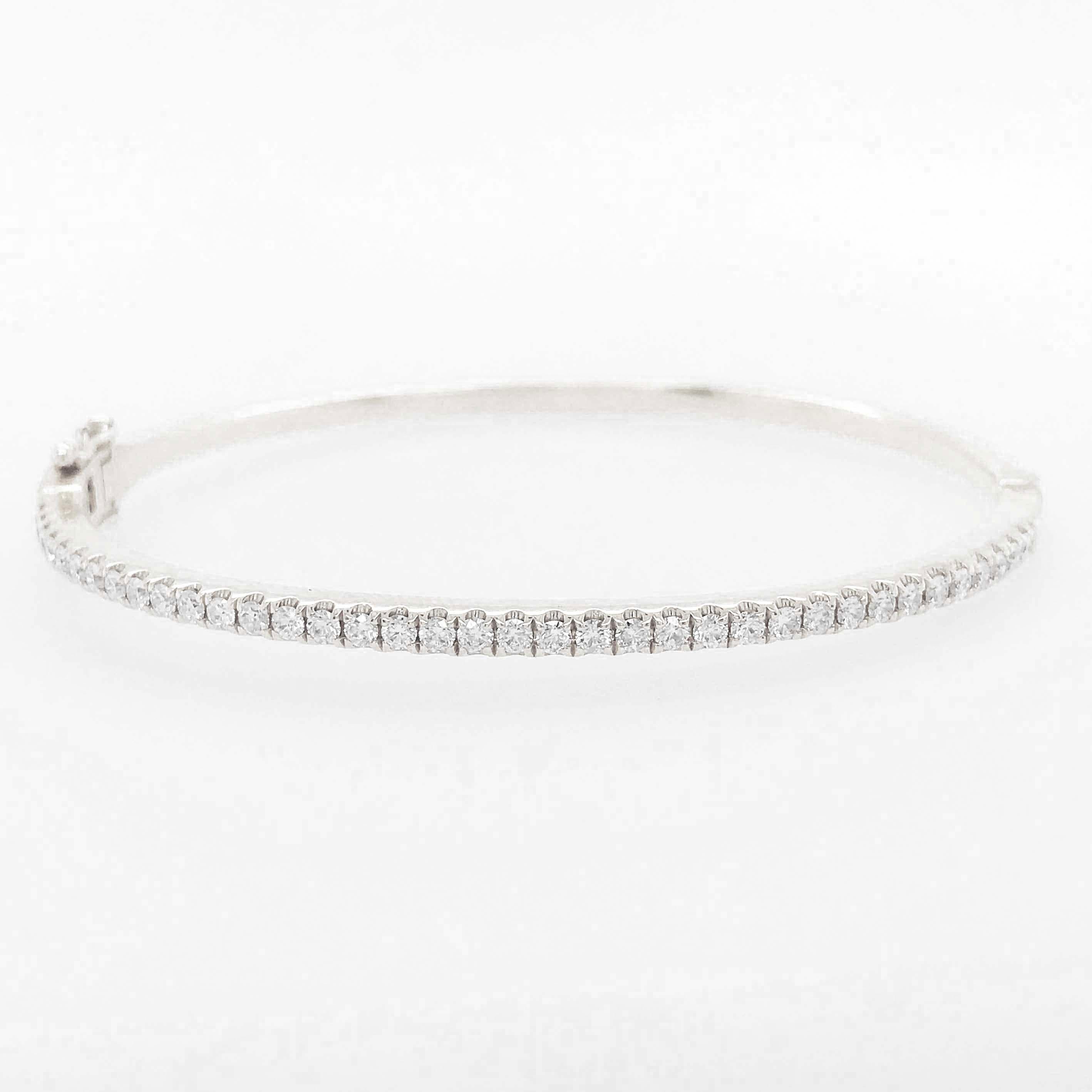 The stunning diamond tennis bangle bracelet is a timeless fine jewelry piece with modern bangle design! The diamond bangle has round brilliant diamonds on the top of the oval shaped bangle bracelet. The diamonds are set in bright white 14k white