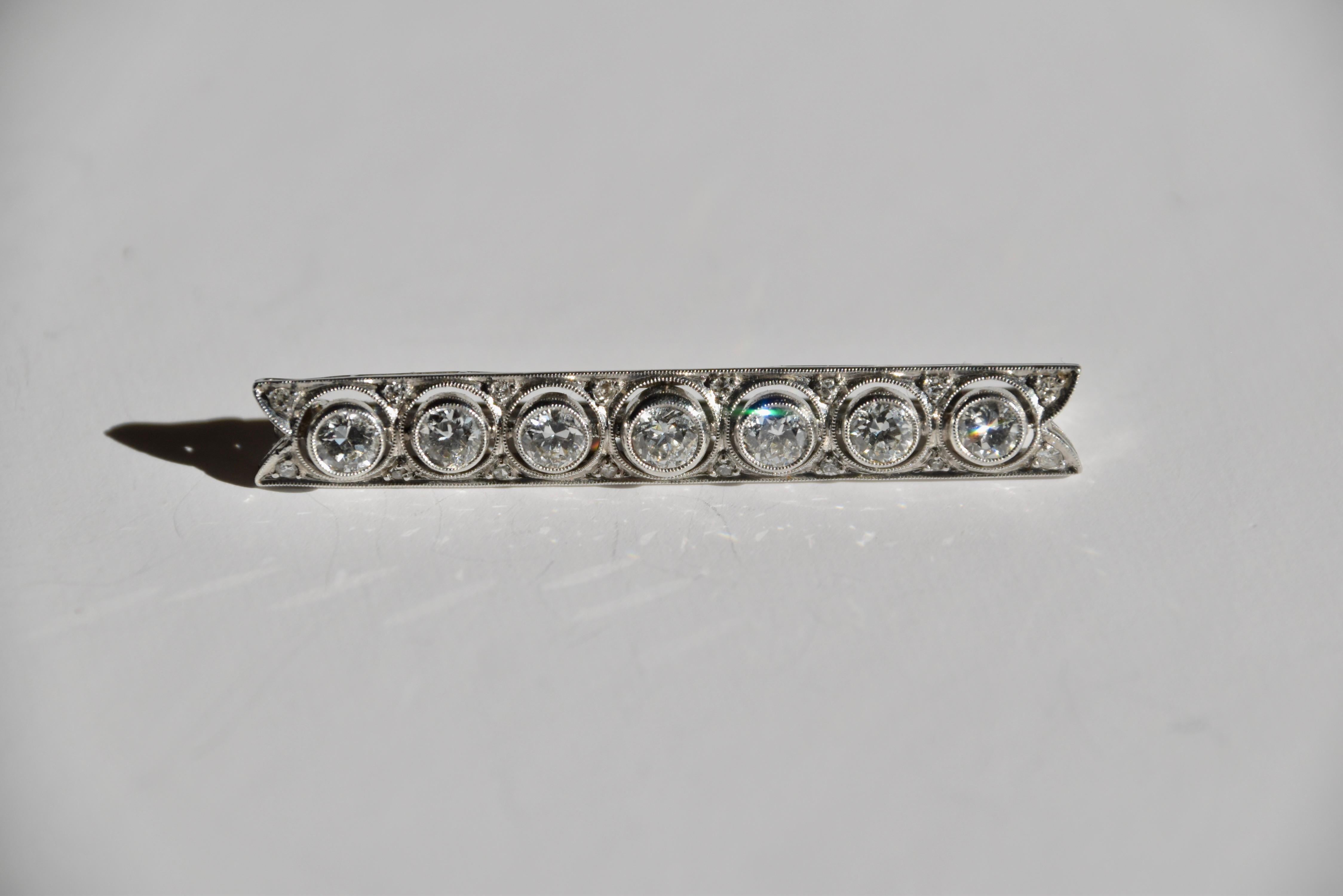 Broche de diamantes de principios del siglo XX con extremos bifurcados, engastado con una línea de diamantes de talla circular que suman aproximadamente 1,25 quilates, espaciados por diamantes más pequeños de talla única montados en platino