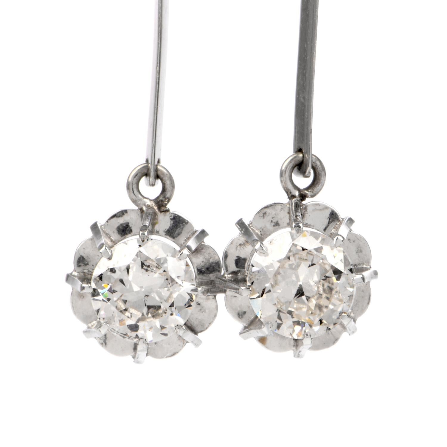 This chic pair of diamond dangle drop earrings is crafted in solid platinum, weighing 3.8 grams and measuring 37mm long x 9mm wide. Centered with a pair of old european-brilliant diamonds prong-set into baskets at the drop and a pair of smaller