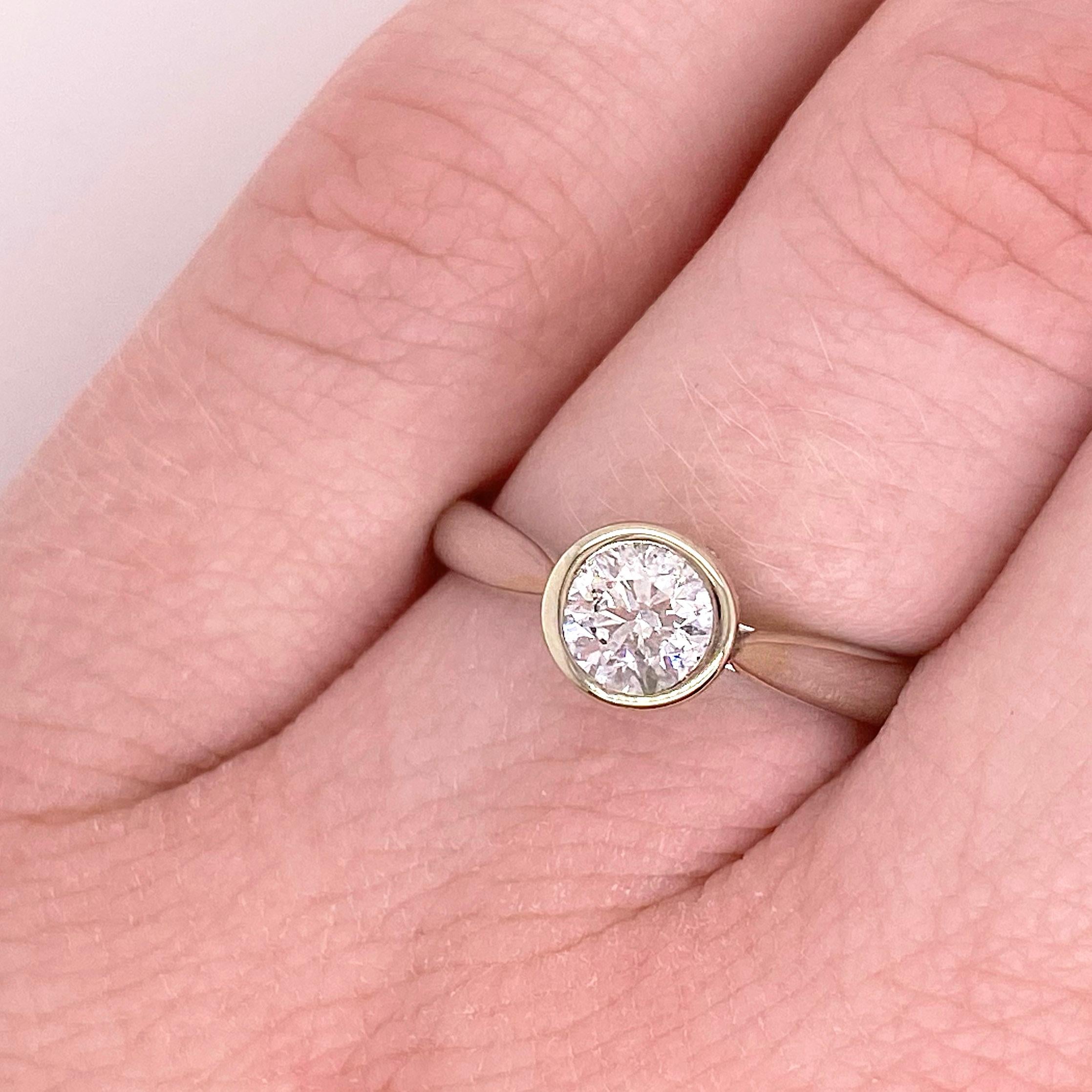 Gorgeous round brilliant cut diamond solitaire engagement ring! This gorgeous center diamond is set in a polished bezel with a hidden halo. The 14 karat white gold engagement ring is the perfect compliment to this stunning round diamond. Very