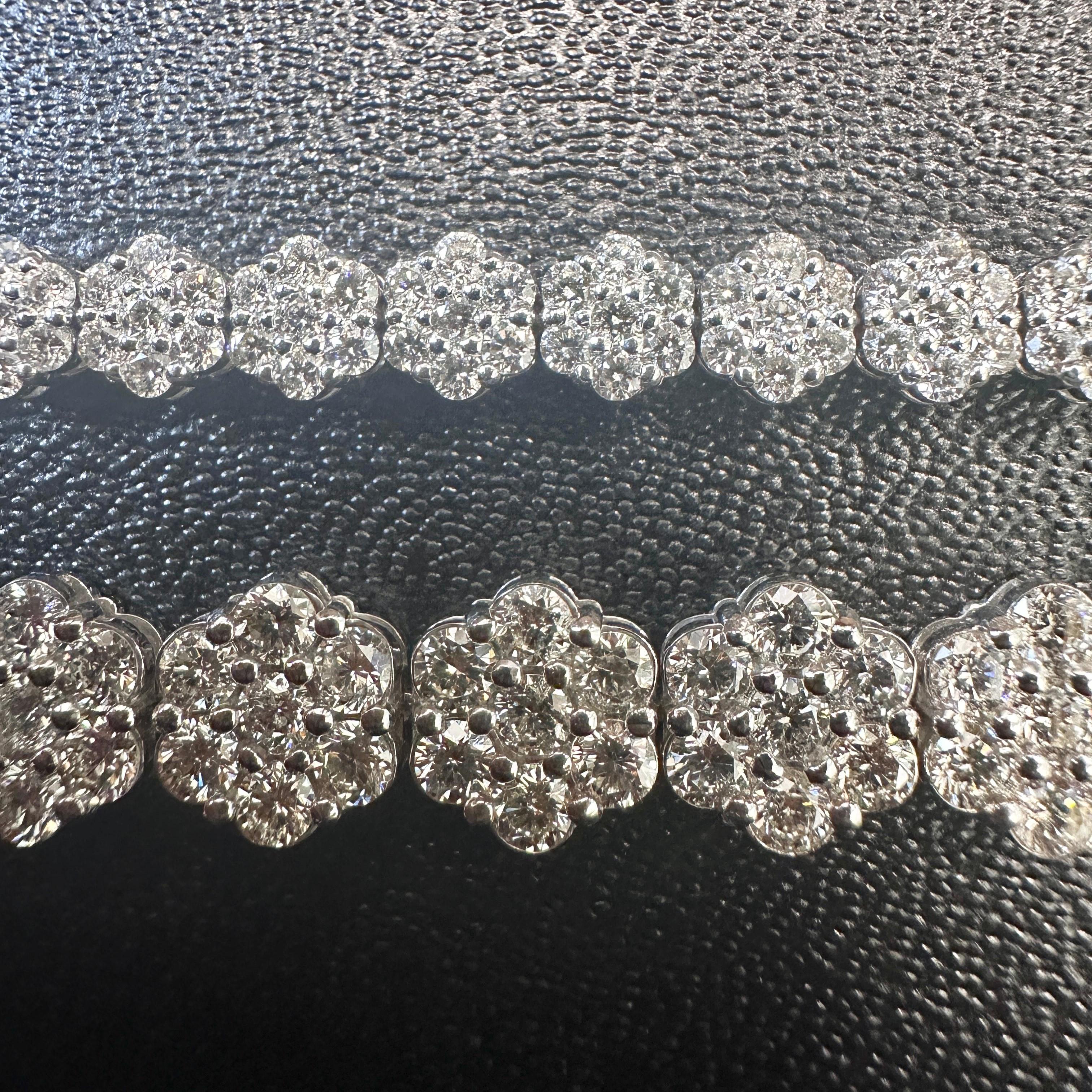 This luxurious 13.85 carat tennis bracelet features an elegant arrangement of round brilliant-cut natural diamonds, clustered into delicate floral motifs. The design delivers bold sparkle with a soft, feminine aesthetic, perfect for both elevated