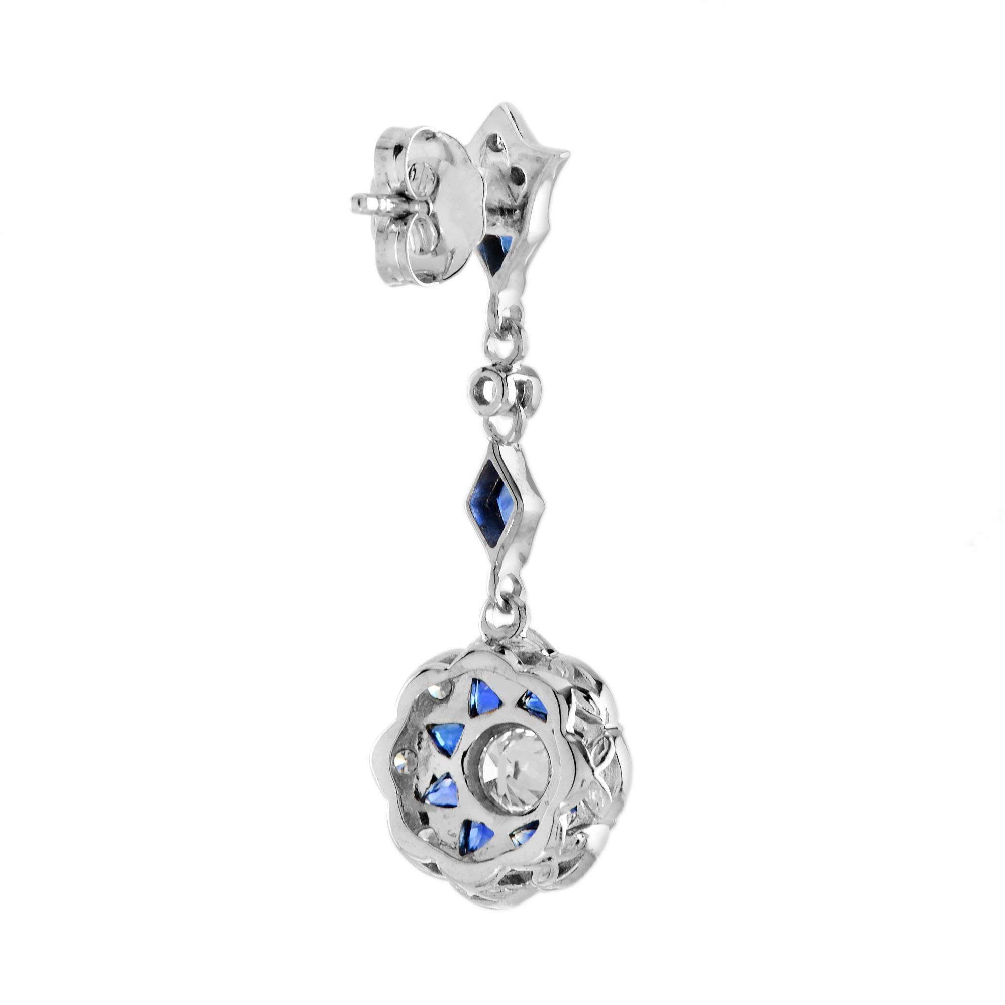 Questi orecchini a goccia di ispirazione Art Déco presentano 0,85 carati di diamanti totali e 2 carati di zaffiri blu rifiniti in un'abbagliante montatura in oro bianco o platino con un antico design floreale. Glamour e fantasiosi, questi orecchini