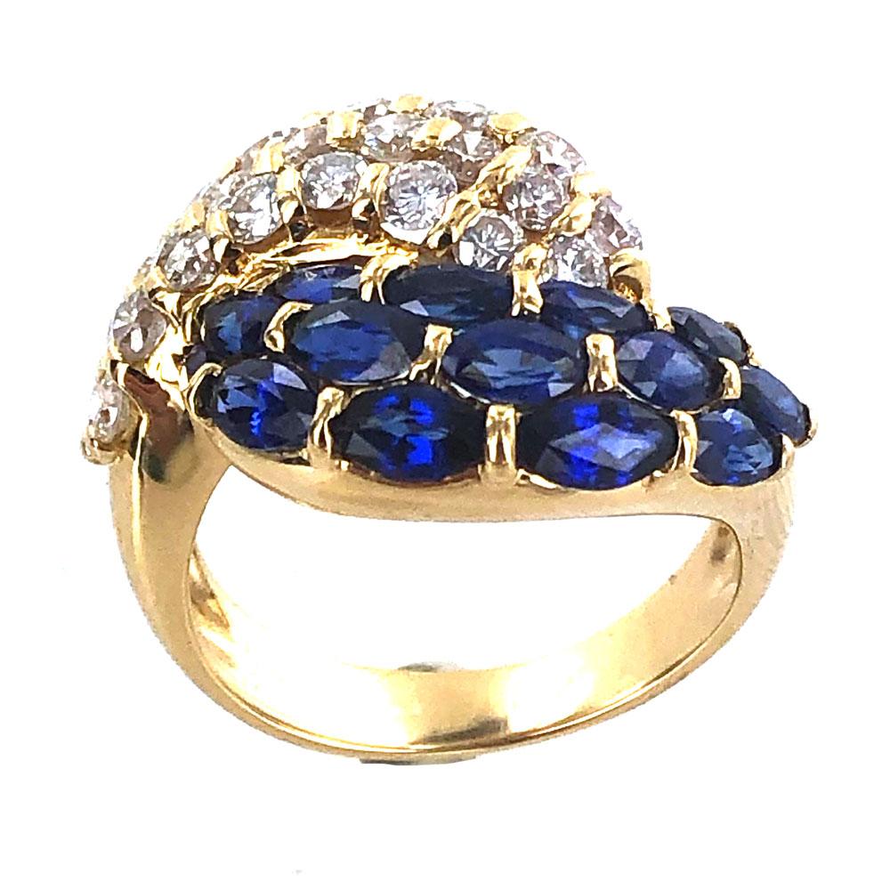 Stunning bypass estate ring fashioned in 18 karat yellow gold. Twenty four round brilliant cut diamonds (1.36 carat total weight) are set in a bypass fashion with 14 marquise cut natural blue sapphires (2.35 carat total weight). The diamonds are