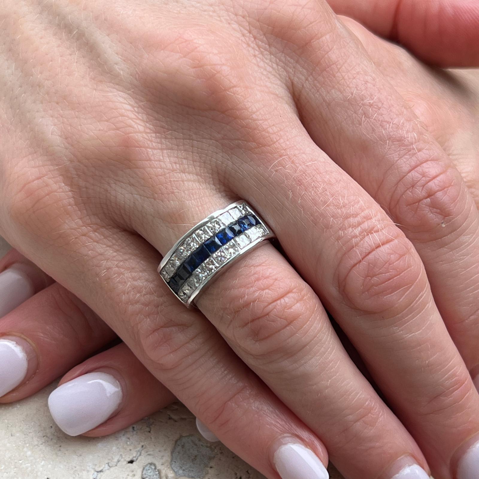 Diamond and blue sapphire invisibly set wedding band crafted in 14 karat white gold. The band features princess cut diamonds weighing approximately 1.60 carat total weight and 10 natural blue square cut sapphires weighing approximately 1.10 CTW. The