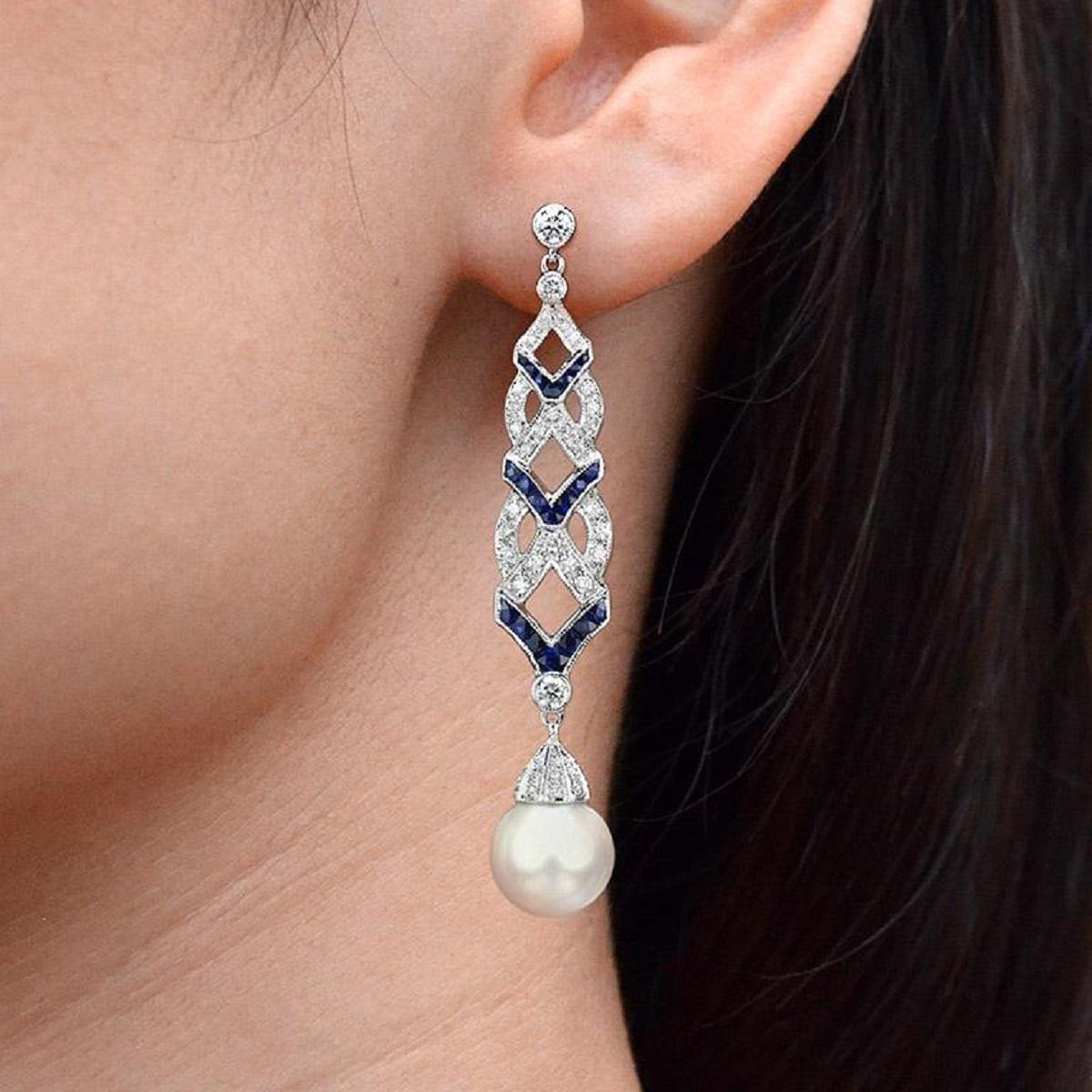 Heben Sie sich von der Masse ab mit diesen hübschen, von Art-Deco inspirierten Ohrringen. An jedem hängt ein Tropfen einer Südseeperle mit einer diamantbesetzten Kappe, darunter gegliederte Linien aus Diamanten und Saphiren. 

Informationen
Stil: