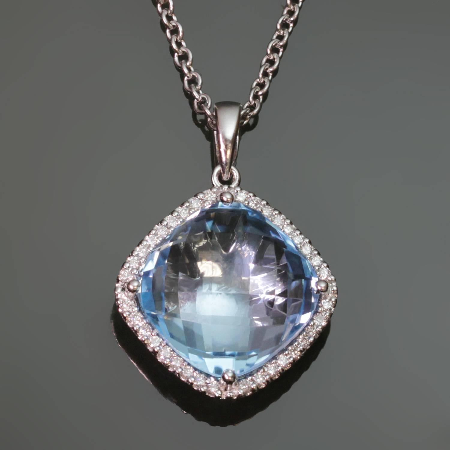 This modern sparkling pendant features a lazer-cut 11.0mm blue topaz surrounded by a row of brilliant-cut round diamonds set in 18k white gold. Completed by a 14k white gold chain.  Measurements: 16mm (5/8
