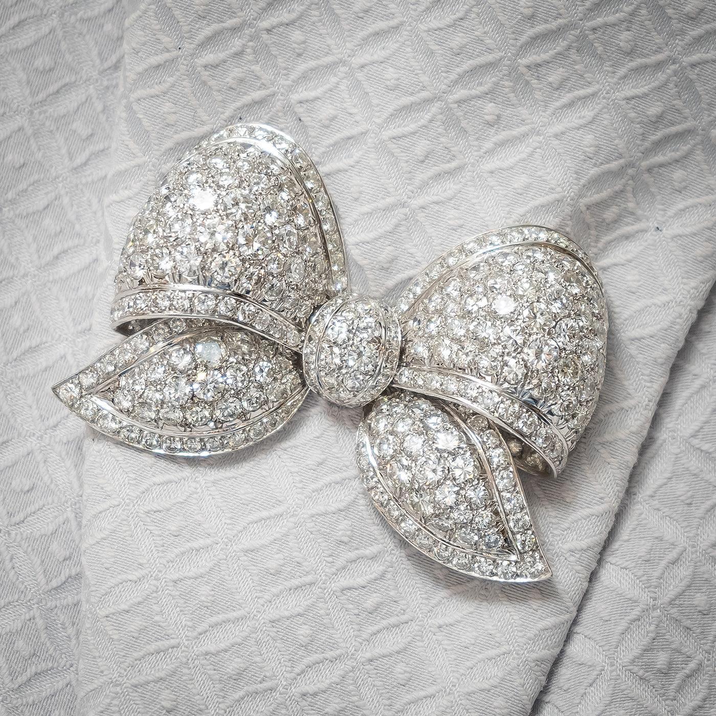 A diamond bow brooch, set with round brilliant cut diamonds weighing an estimated total of 22.00ct, in 18ct white gold. The brooch measures approximately 55 x 40mm.