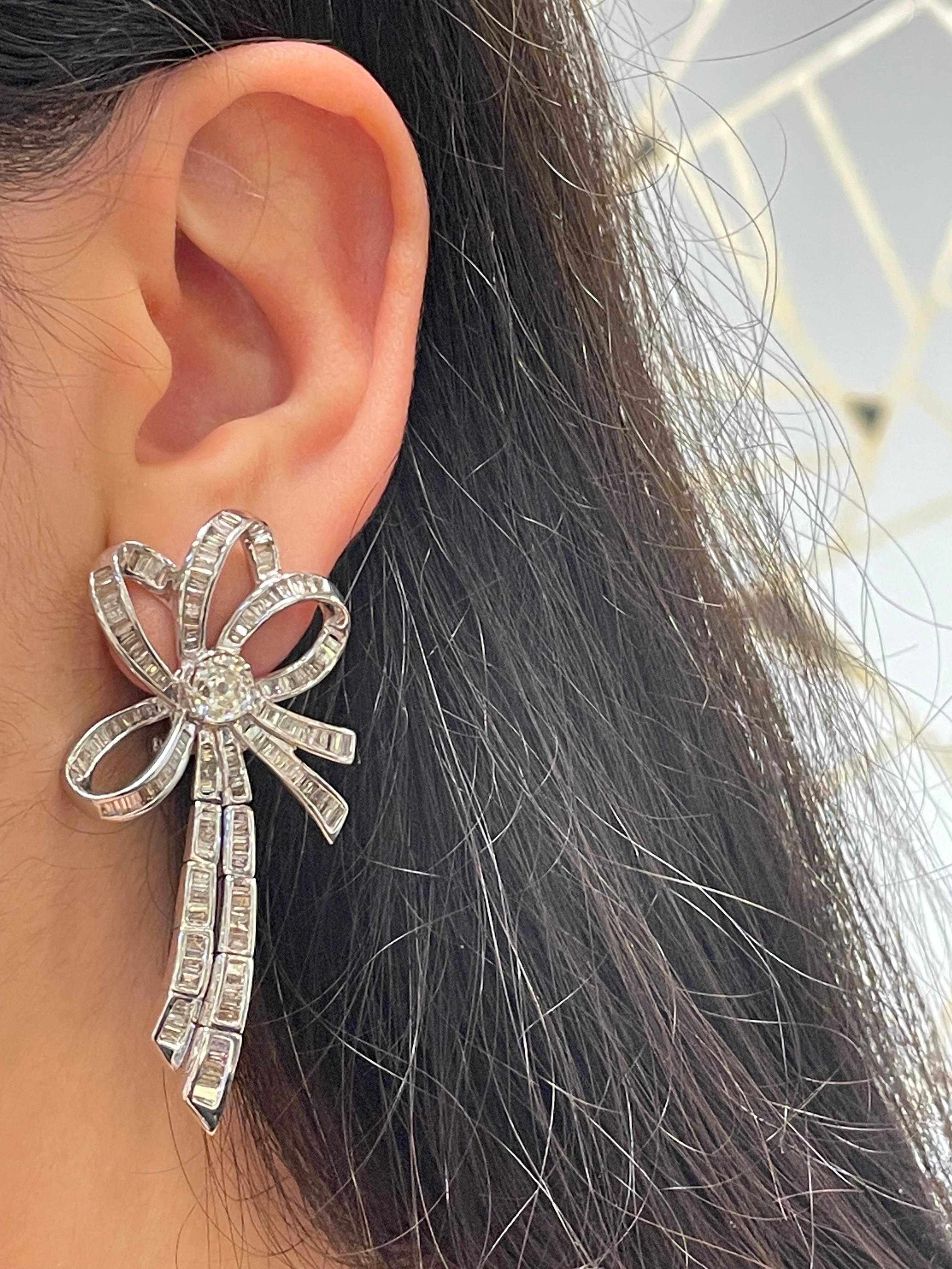 Diamond Bow  Earrings

A large pair of diamond earrings set with two center old cut diamonds and 299 baguette cut diamonds. 

Approximate combined diamond weight: 6.23 carats
Approximate Length 2