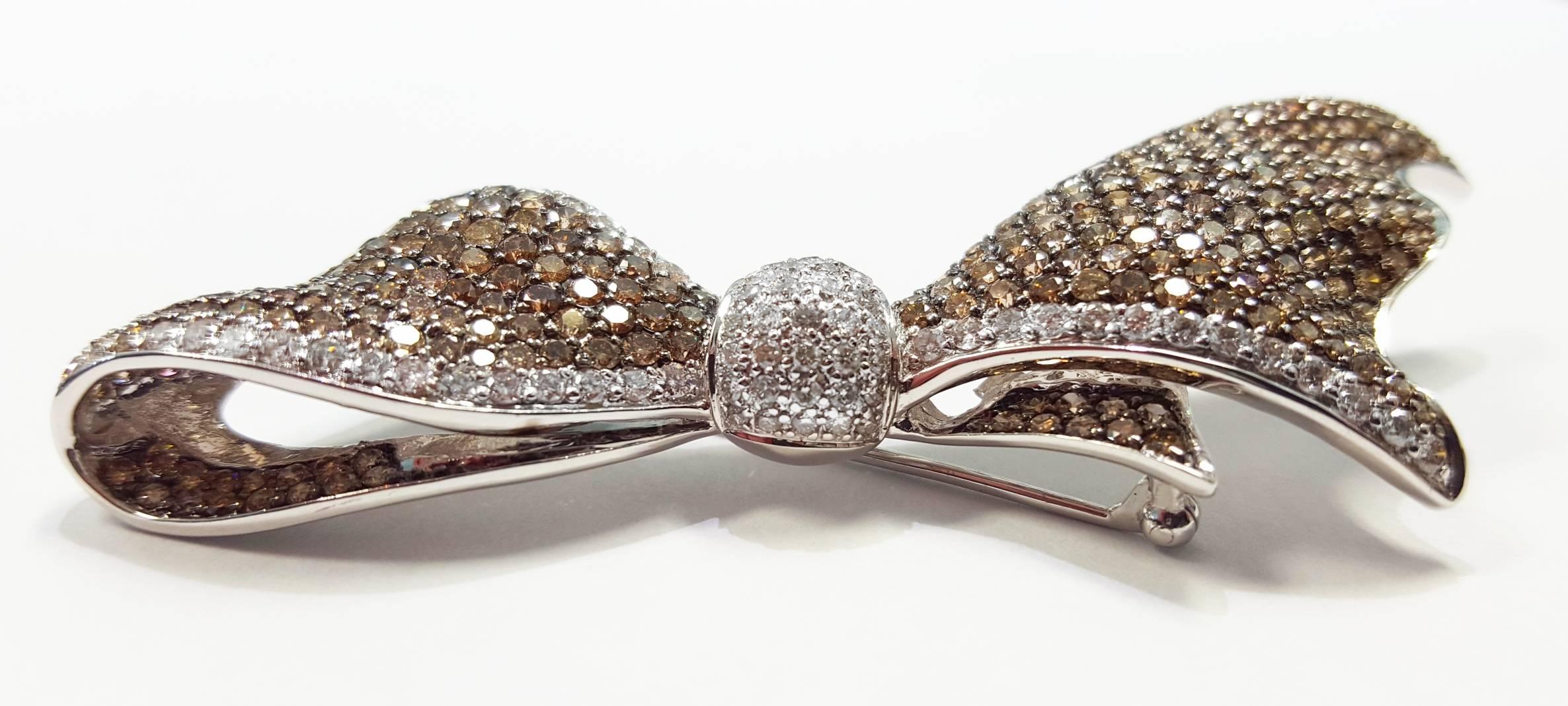 A white gold bow pin set with 280 round brilliant cut diamonds. The diamonds are fancy brown color and white. The diamonds have a total weight of 6.58cttw. The pin measures 3 inches long and 1 inch wide. The pin weighs 10.8dwt