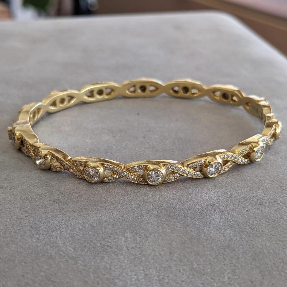 Diamond Braided Bangle Bracelet Hinged in 18k Yellow Gold

Diamond Bangle features two intertwining rows of Diamonds set with 7 larger Bezel set Diamonds on top half of bracelet all set in 18k Yellow Gold. The bottom half of the bracelet has no
