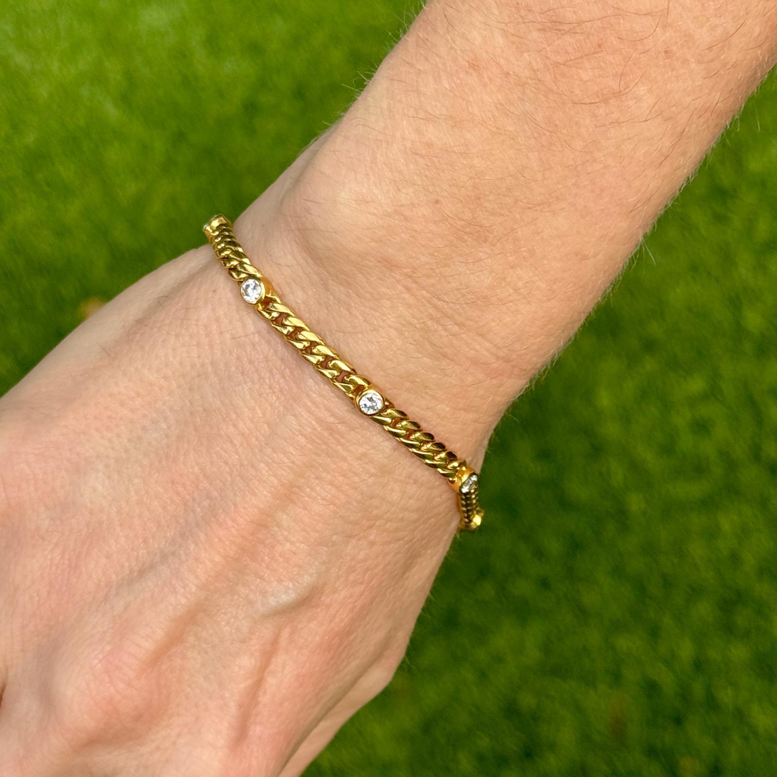 Diamond by the yard curb link bracelet crafted in 18 karat yellow gold.. The bracelet features 8 bezel set round brilliant cut diamonds weighing approximately 1.00 carat total weight. The diamonds are graded G-H color and SI1 clarity. The bracelet