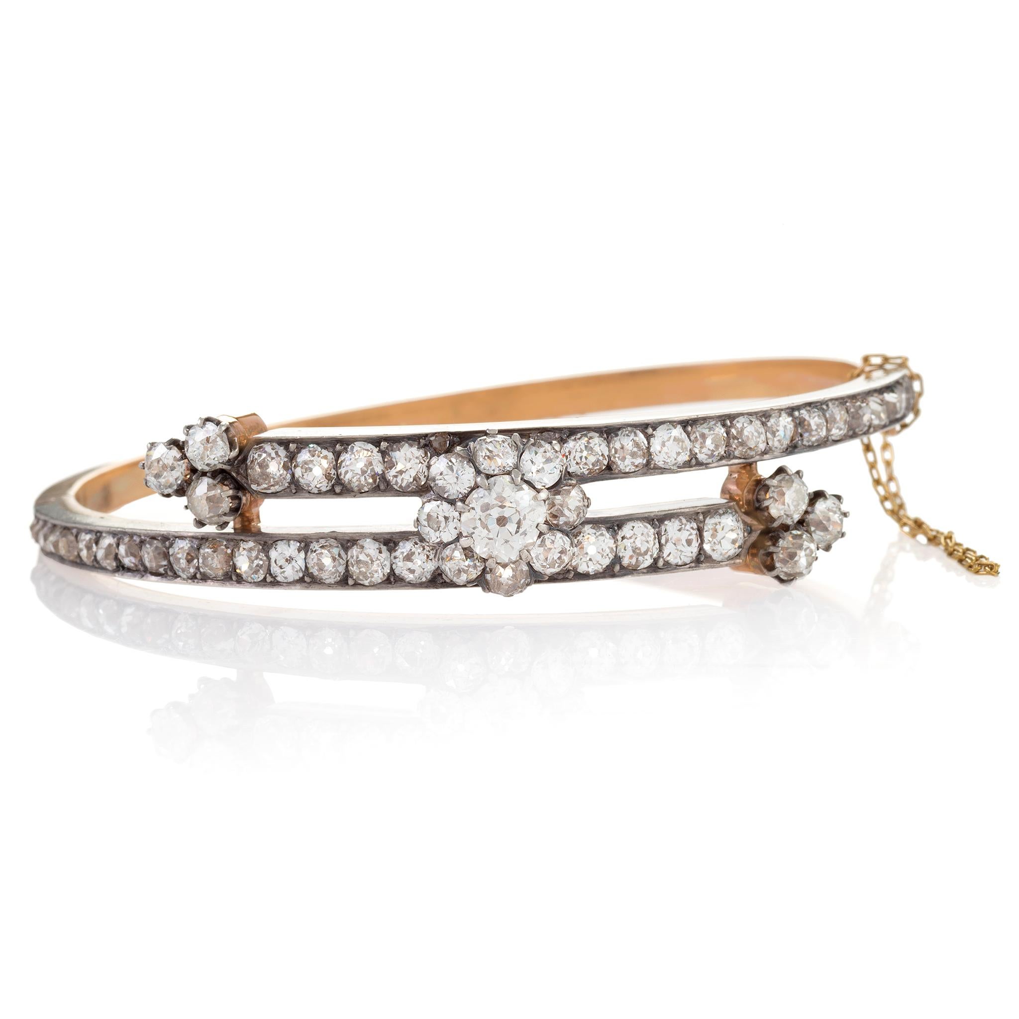 Dating from the late 19th century, this sparkling bypass bangle bracelet is set with nearly sixty old mine-cut diamonds weighing, in total, close to six carats. Designed as a platinum-topped gold bypass form, with the top section bead-set throughout
