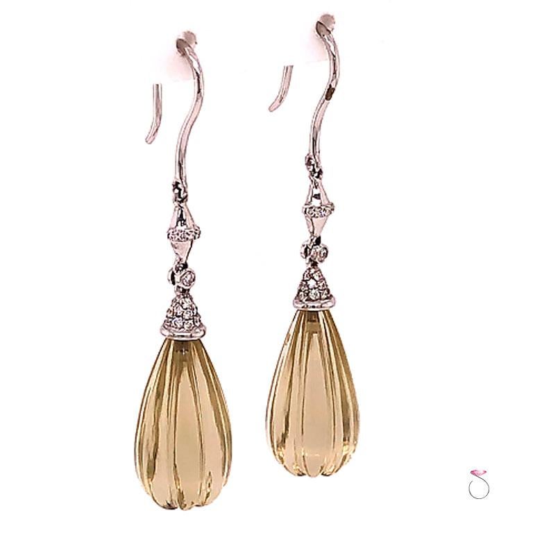 Stunning carved Lemon Quartz & Diamond drop earrings in 18k white gold. These beautiful earrings feature two large carved drop pear shape Lemon Quartz gems totaling approximately 14.00 carats. The Lemon Quartz are set in a 18k white cap set with
