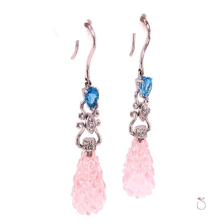 Stunning carved Pink Quartz, Blue Topaz & Diamond drop earrings in 18k white gold. These beautiful earrings feature two large carved drop pear shape Pink Quartz gems totaling approximately 14.00 carats. The Pink Quartz are set in 18k white caps
