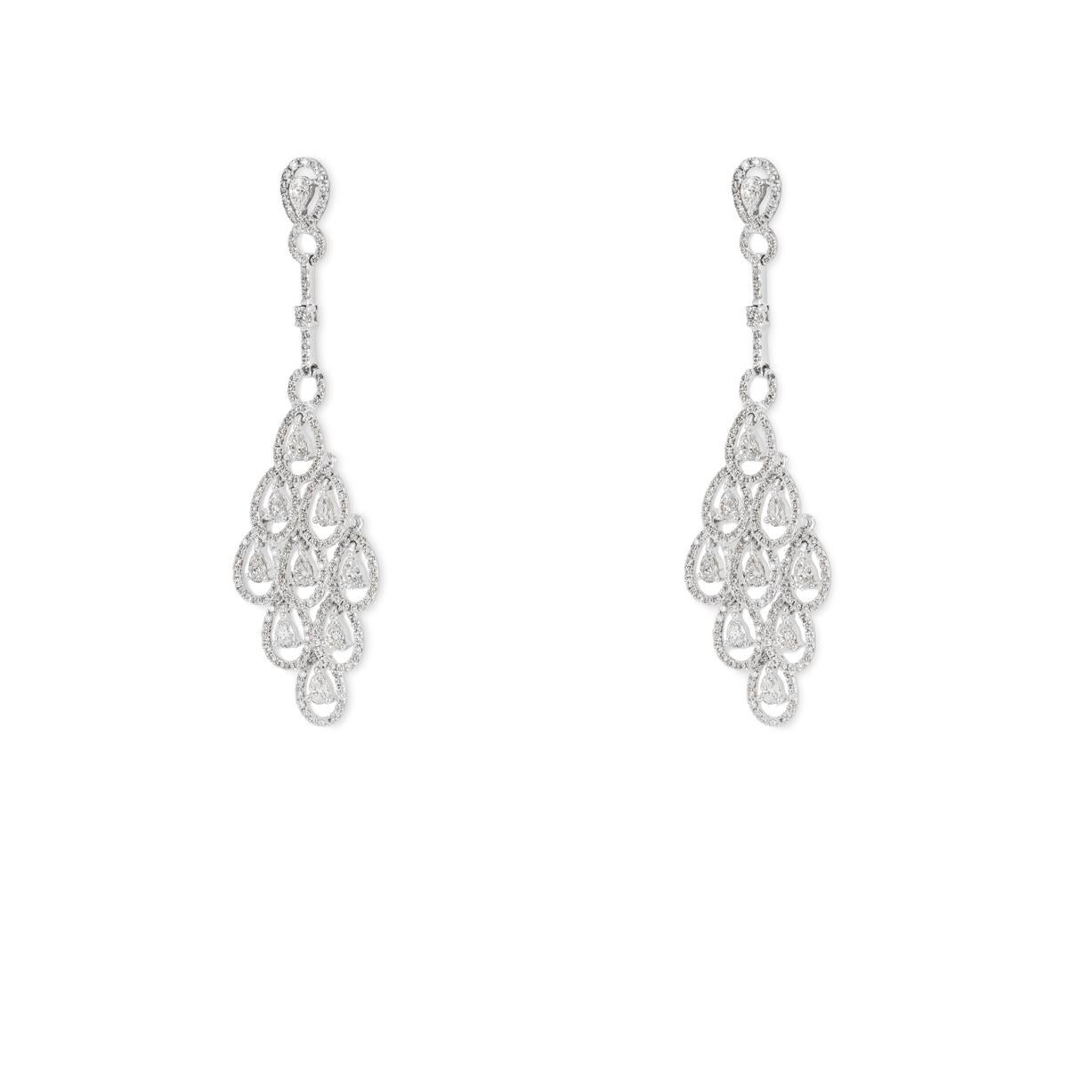 A pair of 18k white gold diamond chandelier motif drop earrings. The earrings features an openwork design with round brilliant cut diamonds in a pave setting around the outer edge with pear cut diamonds and a single round brilliant cut diamond. The