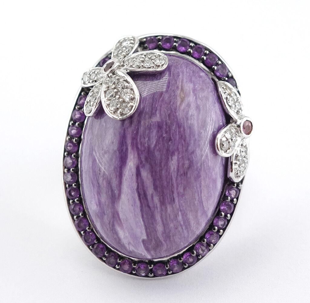 This absolutely stunning estate ring is finely crafted in solid 14K White Gold and set with genuine Russian Charoite, Diamonds, and Amethysts.
The center Charoite cabochon measures 24mm (1 inch) x 18mm. 
It is surrounded by thirty genuine Earth