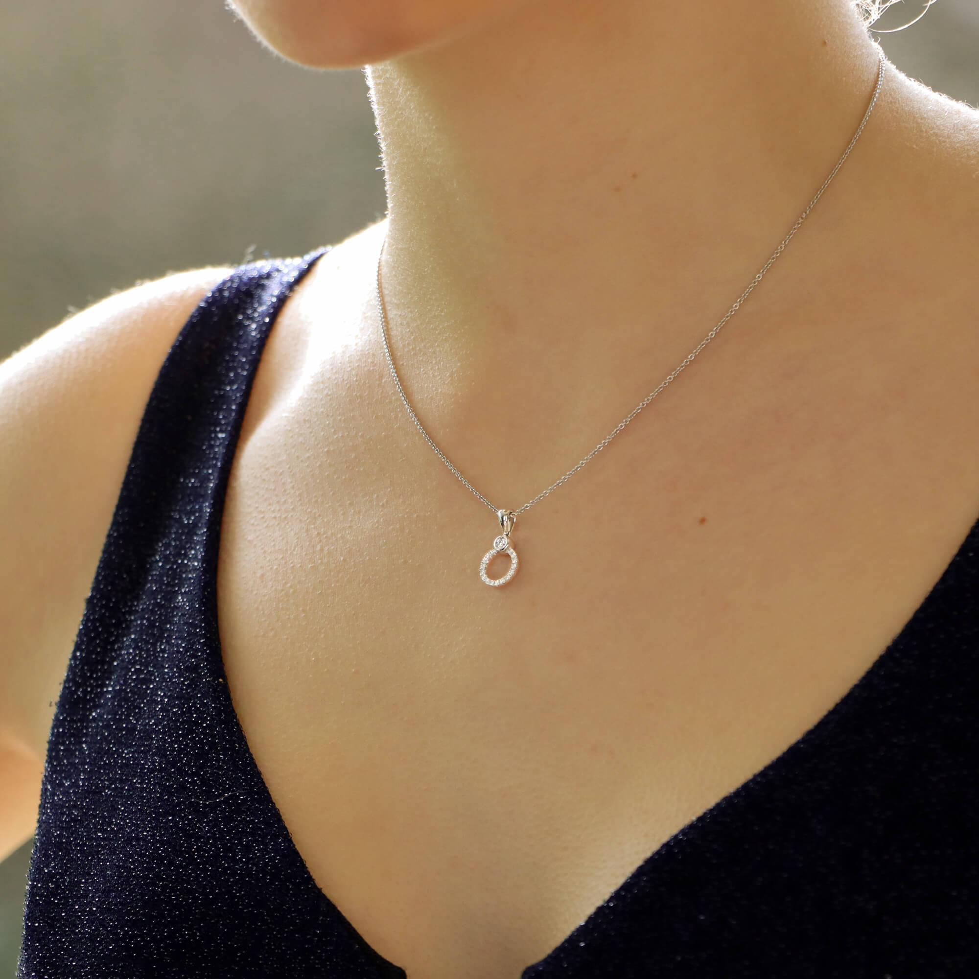 Un bellissimo pendente a forma di cerchio con diamante incastonato in oro bianco 18 carati.

Questo semplice ciondolo è incastonato con un grande diamante rotondo taglio brillante da 0,04 carati, racchiuso in una montatura rub-over. Il resto del