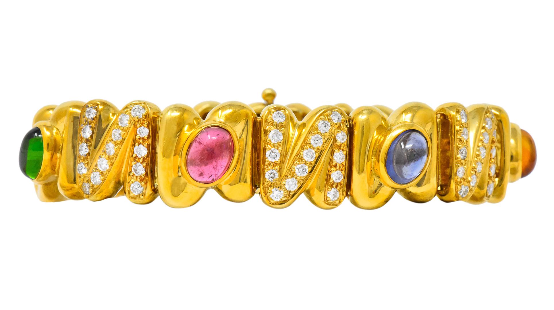 Featuring polished gold squiggle links with bezel set brightly colored oval cabochon gemstones measuring 8.0 x 6.4 mm

Gemstones include green and pink tourmaline, citrine, amethyst, and iolite as well as round brilliant cut diamonds weighing
