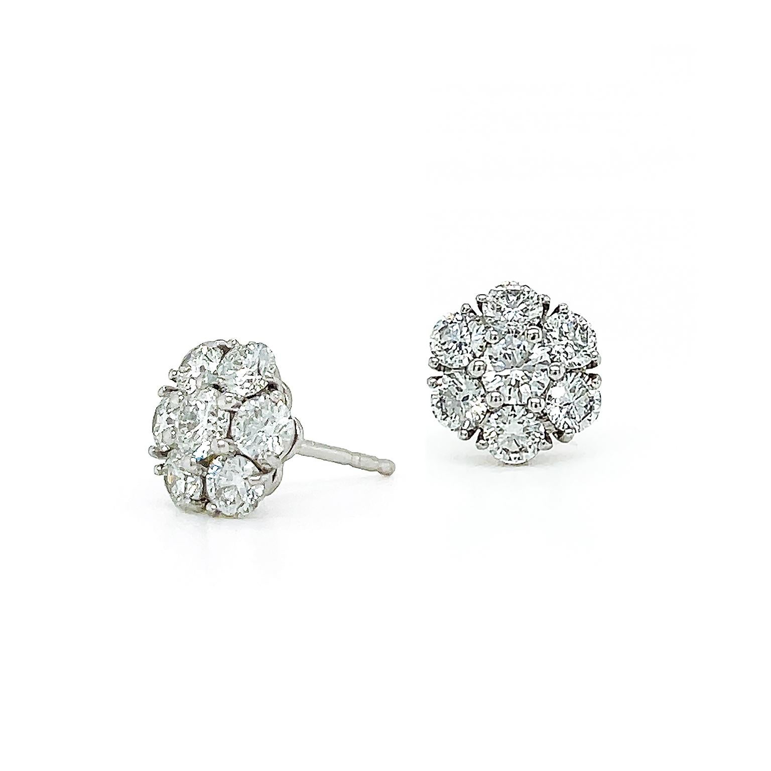 The radiance of brilliant cut diamonds is illustrated in these earrings. A single diamond in the center is surrounded by six diamonds, all set in platinum for a cohesive look to allow the gem to glisten. Attached by European back post and clutch,