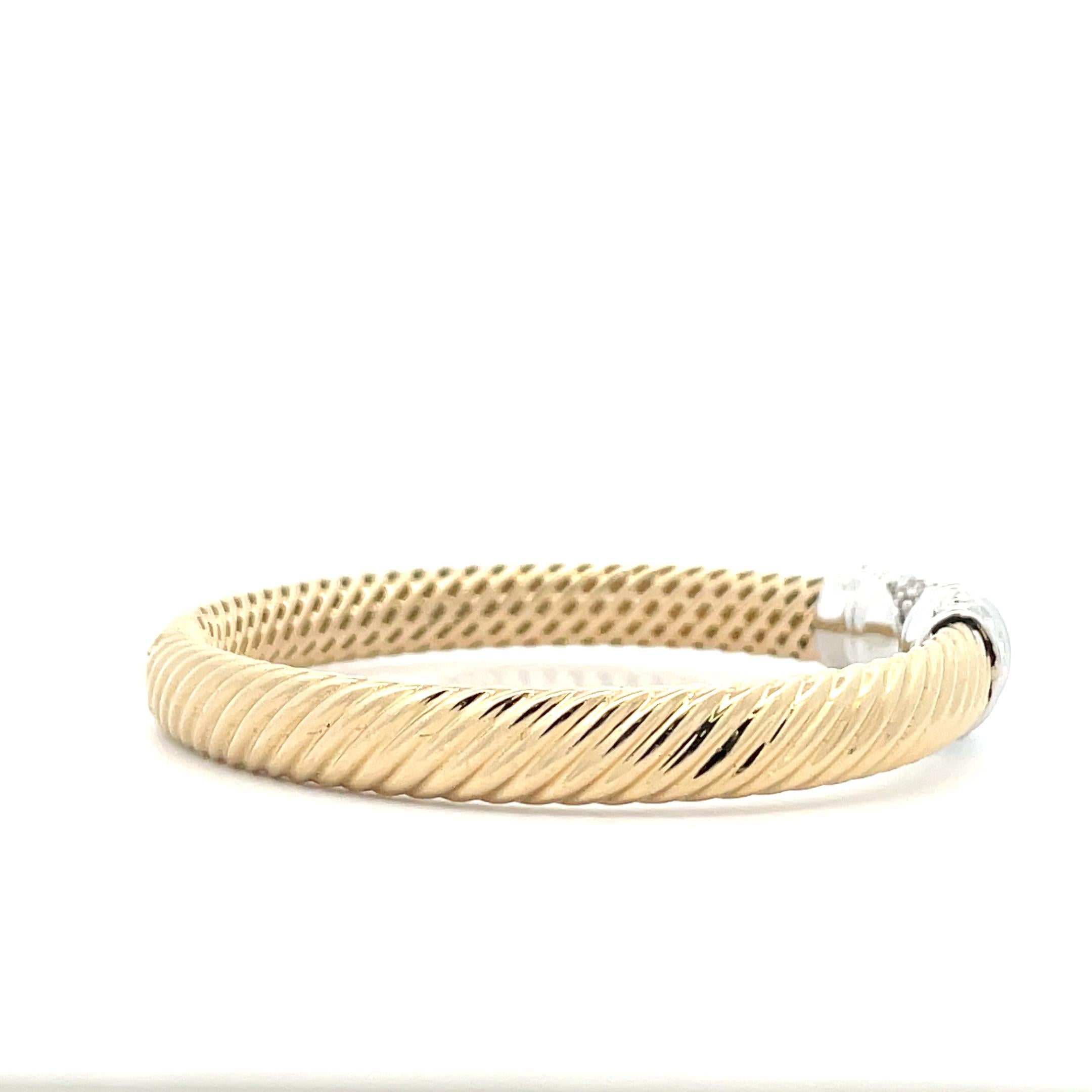 This sculpted bangle of solid 14K gold has been carved with a cable motif, adding subtle movement to this timeless design. The ends of each bangle have been decorated with cluster of white diamonds for added sparkle. Wear it alone or with other