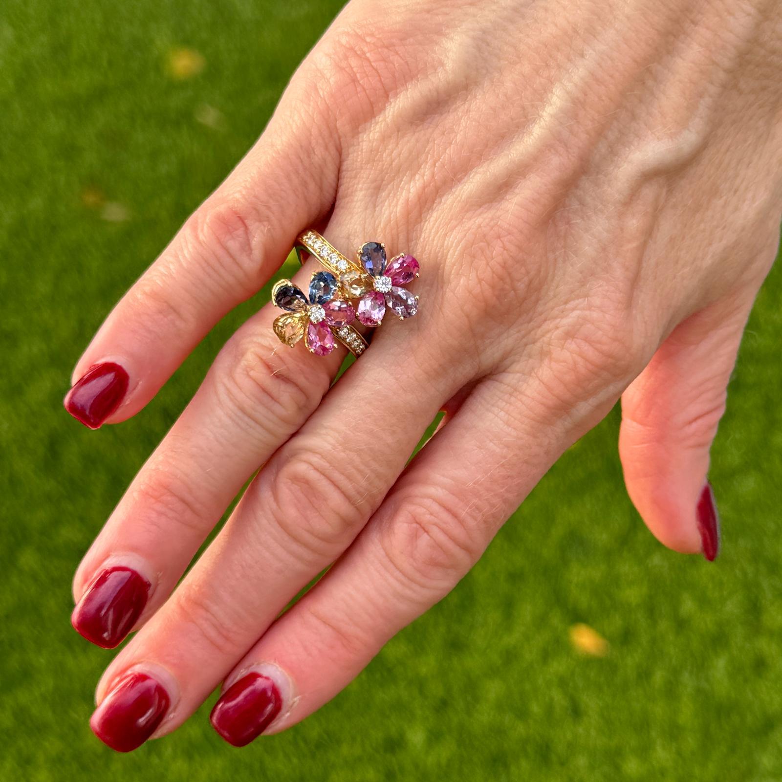 Questo anello bypass floreale in oro giallo a 14 carati presenta un design affascinante con diamanti scintillanti e vibranti gemme colorate. Dodici diamanti rotondi a taglio brillante, per un totale di circa 0,24 carati, hanno un colore G-H e una