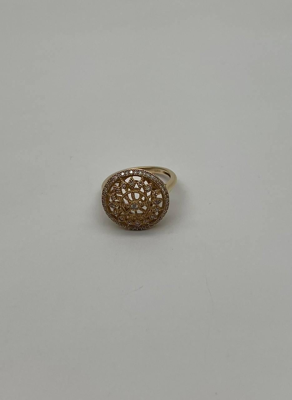 A study in intricate design and golden elegance.
This captivating ring features a stunning circular oval compass motif. The intricate latticework is adorned with sparkling diamonds, creating a mesmerizing pattern. The central design is framed by a