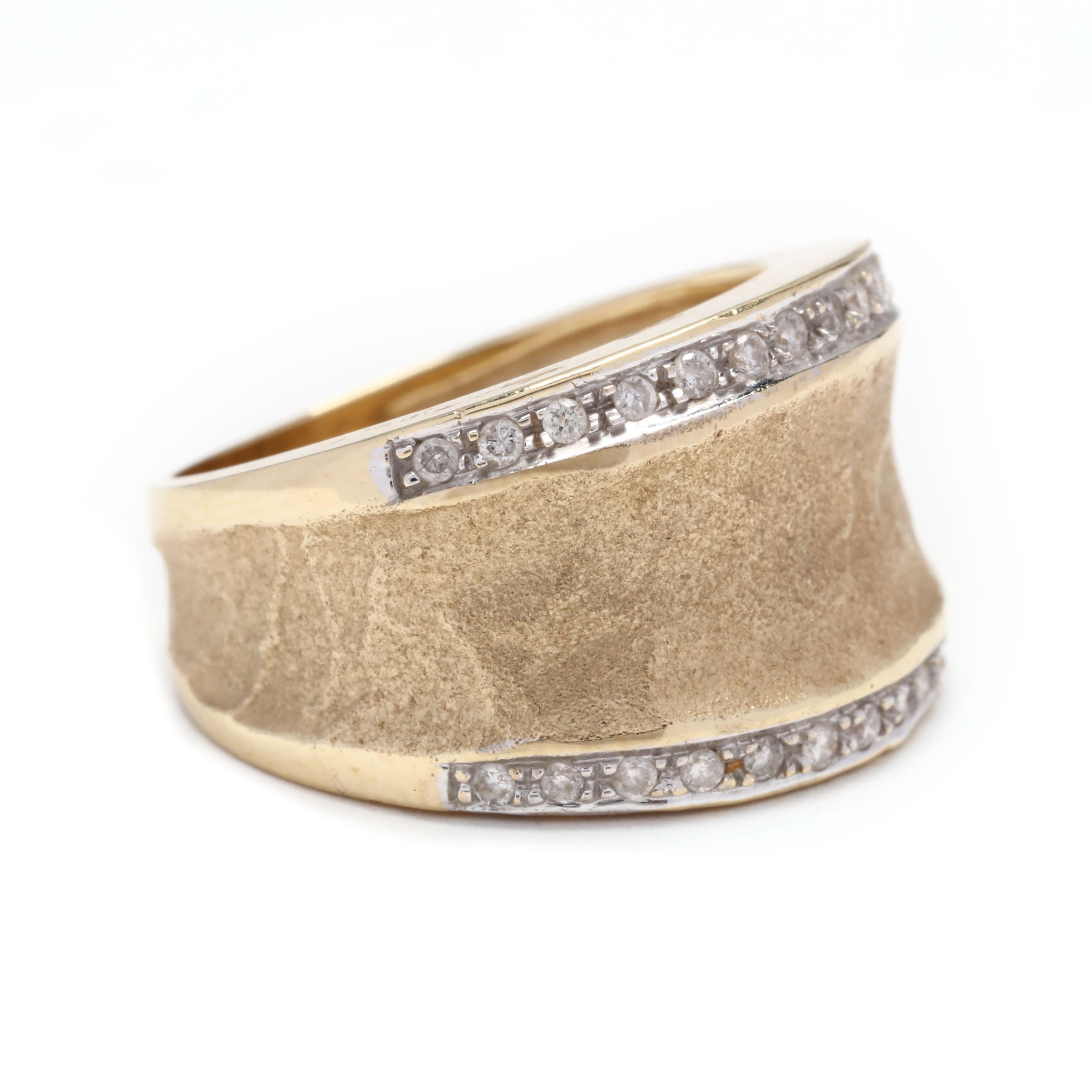 A 14 karat yellow and white gold diamond concave hammered wide band. This band features a wide concave tapered design with a matte hammered finish in the center and a row of pavé set diamonds on either side weighing approximately .26 total