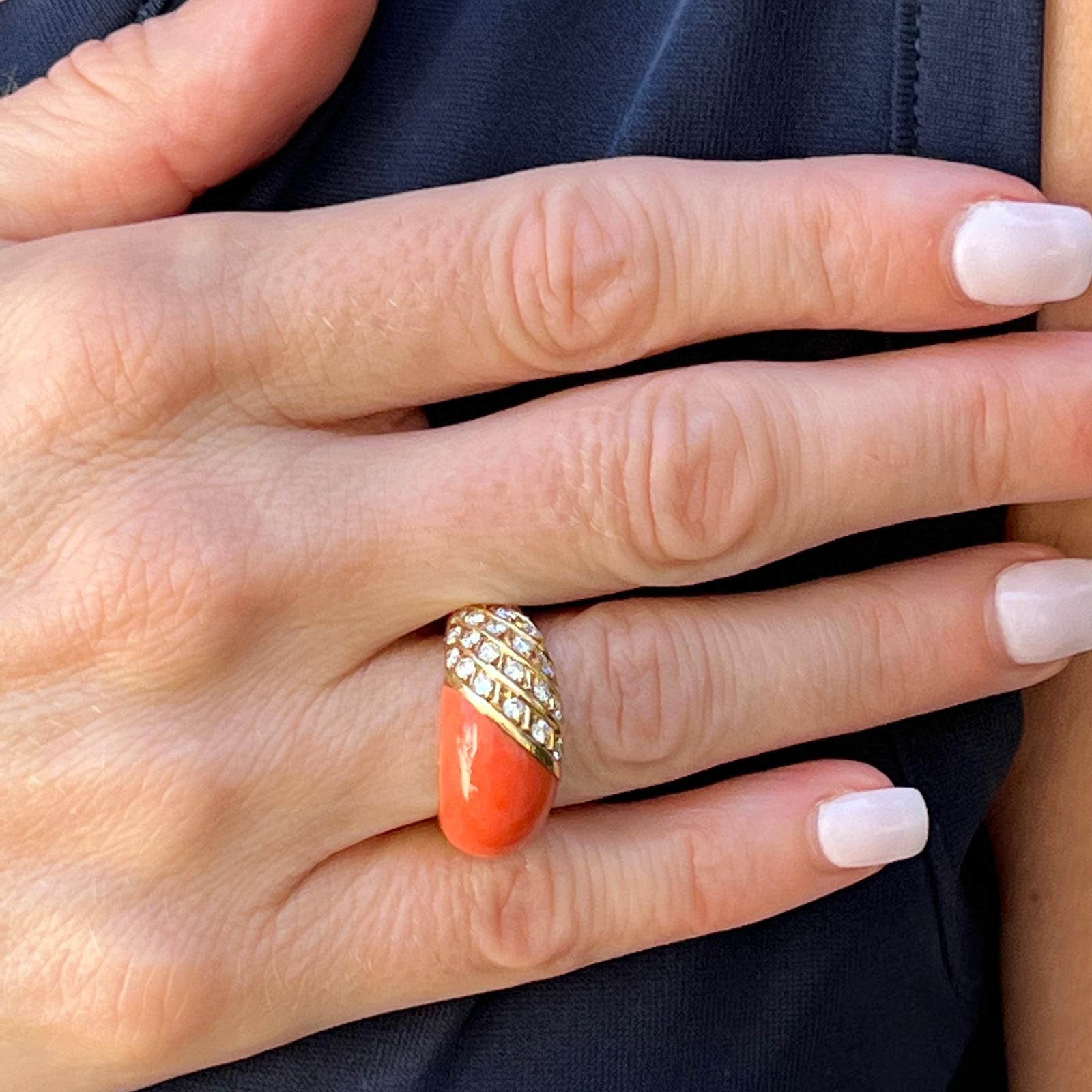 Beautiful diamond and coral dome ring handcrafted in 18 karat yellow gold. The ring features 26 round brilliant cut diamonds weighing approximately .78 carat total weight and graded G-H color and VS clarity. The cabochon coral has a rich orange