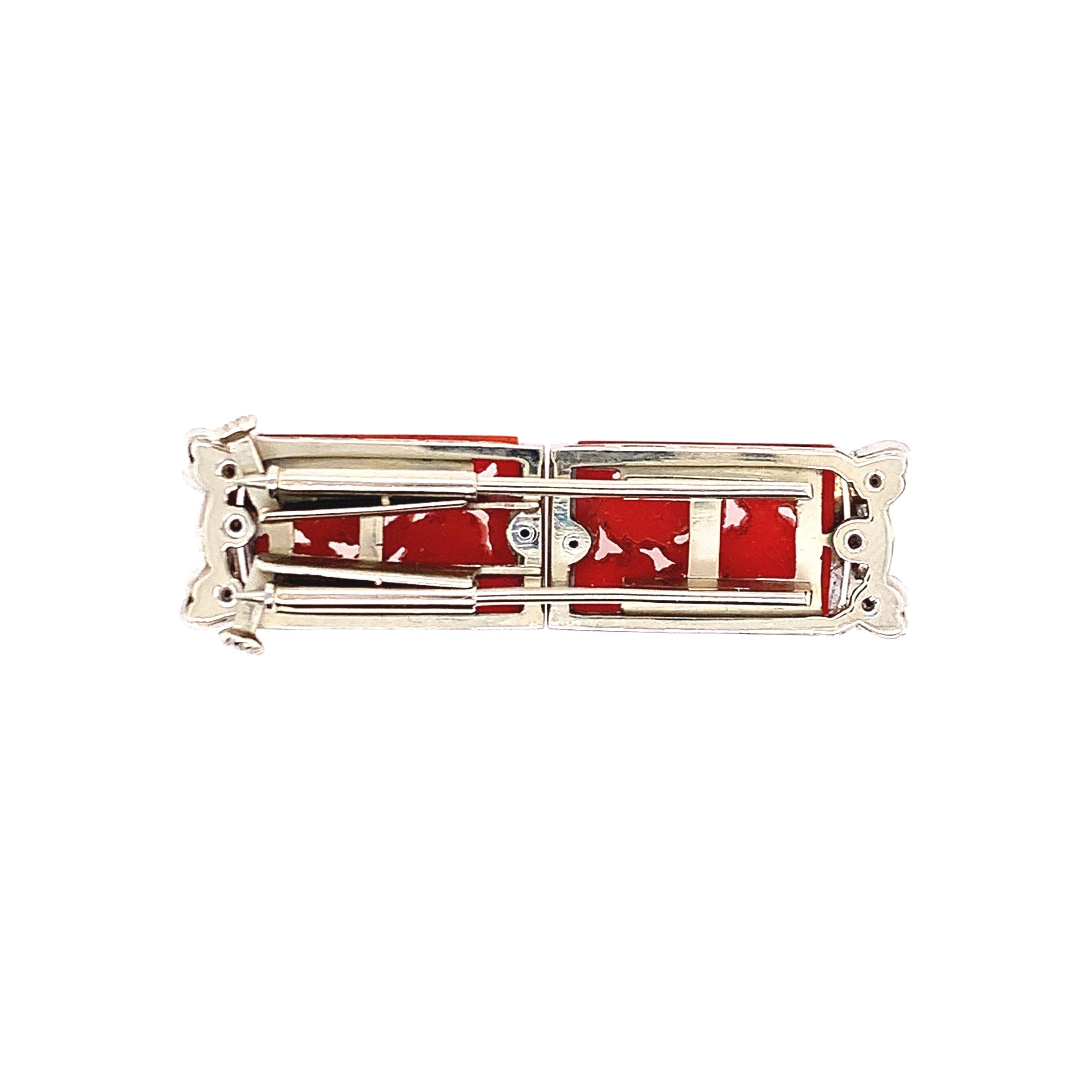 An art deco style, this brooch has diamonds totaling 0.20 carat and two pieces of corals set in platinum. The length is approximately 0.5 inch and the width is 1.75 inches. The total weight is 11.7 grams. 