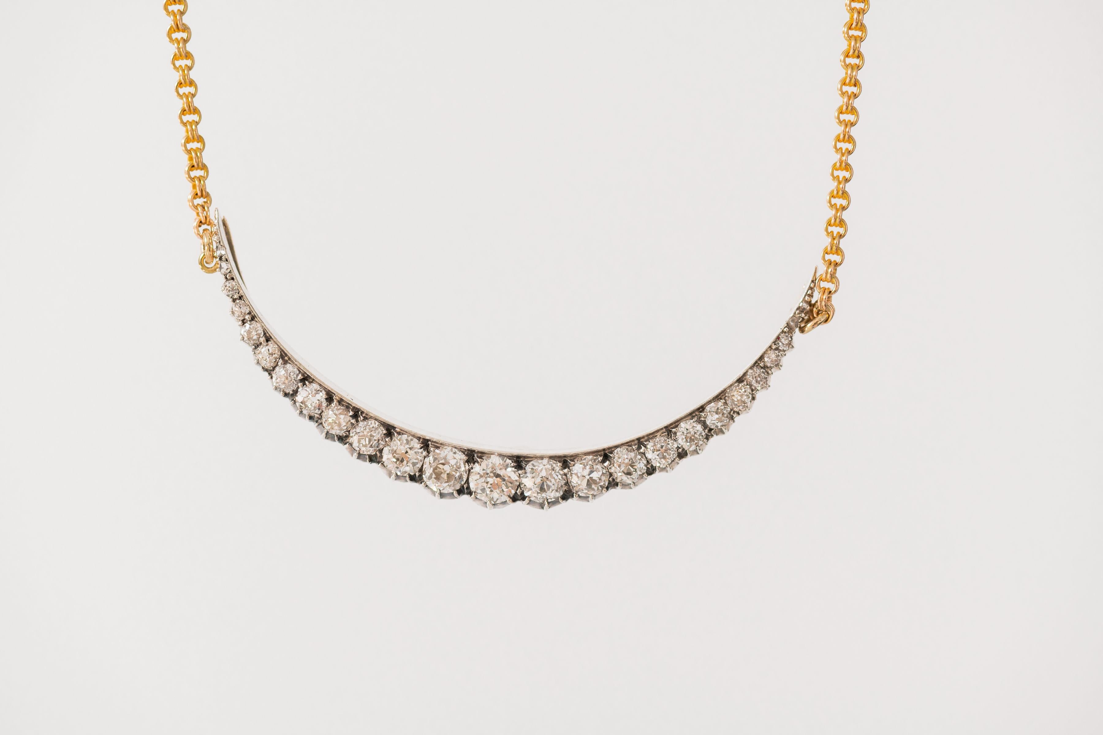 Victorian diamond and yellow gold and silver crescent pendant circa 1900, with 23 graduated diamonds, approximately 2 ct in total on a yellow 14K chain of a later date.