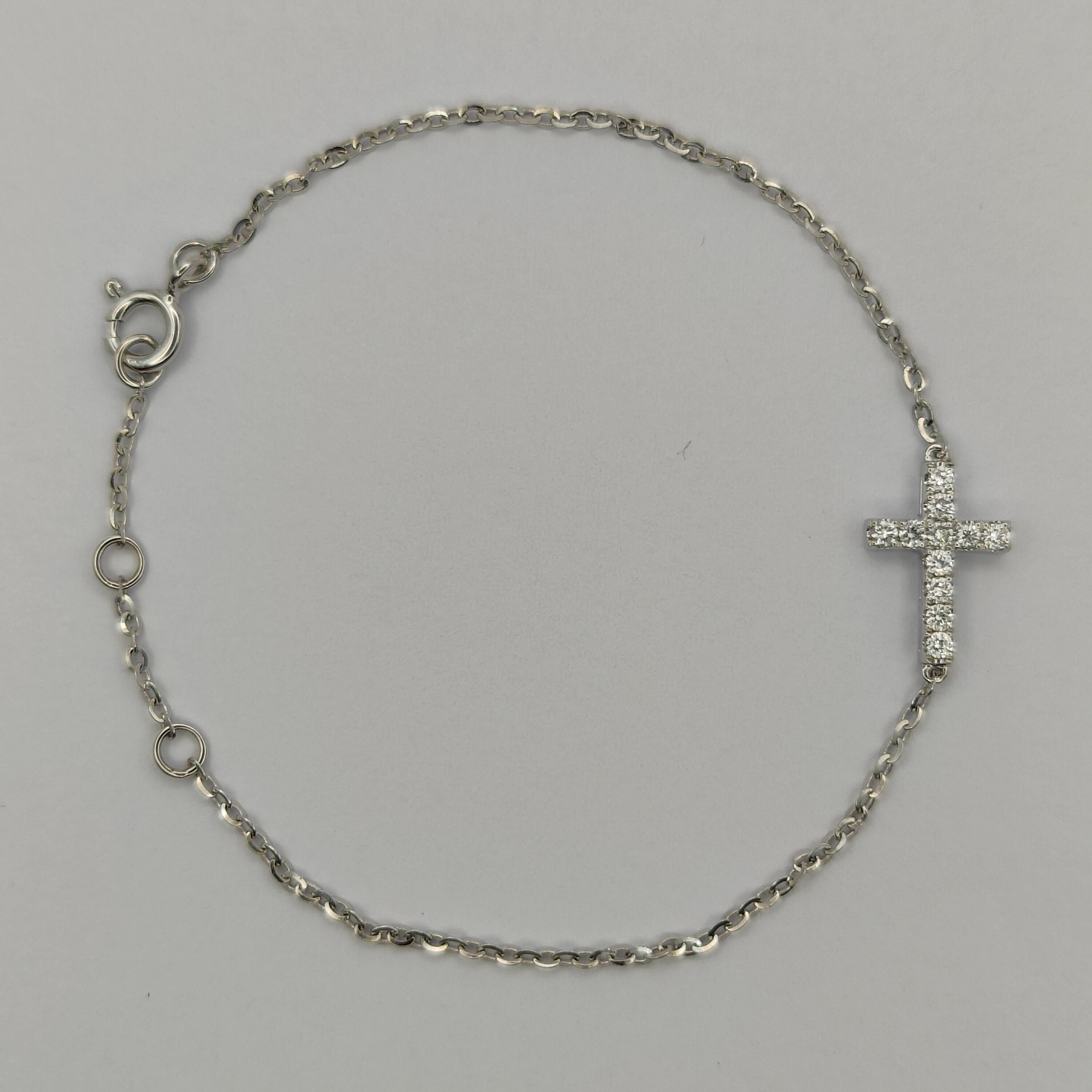 This beautiful diamond bracelet features a delicate white gold chain adorned with a sparkling diamond cross pendant. The bracelet is made of 18k white gold, giving it a timeless and elegant appearance. The pendant is set with 11 high-quality round