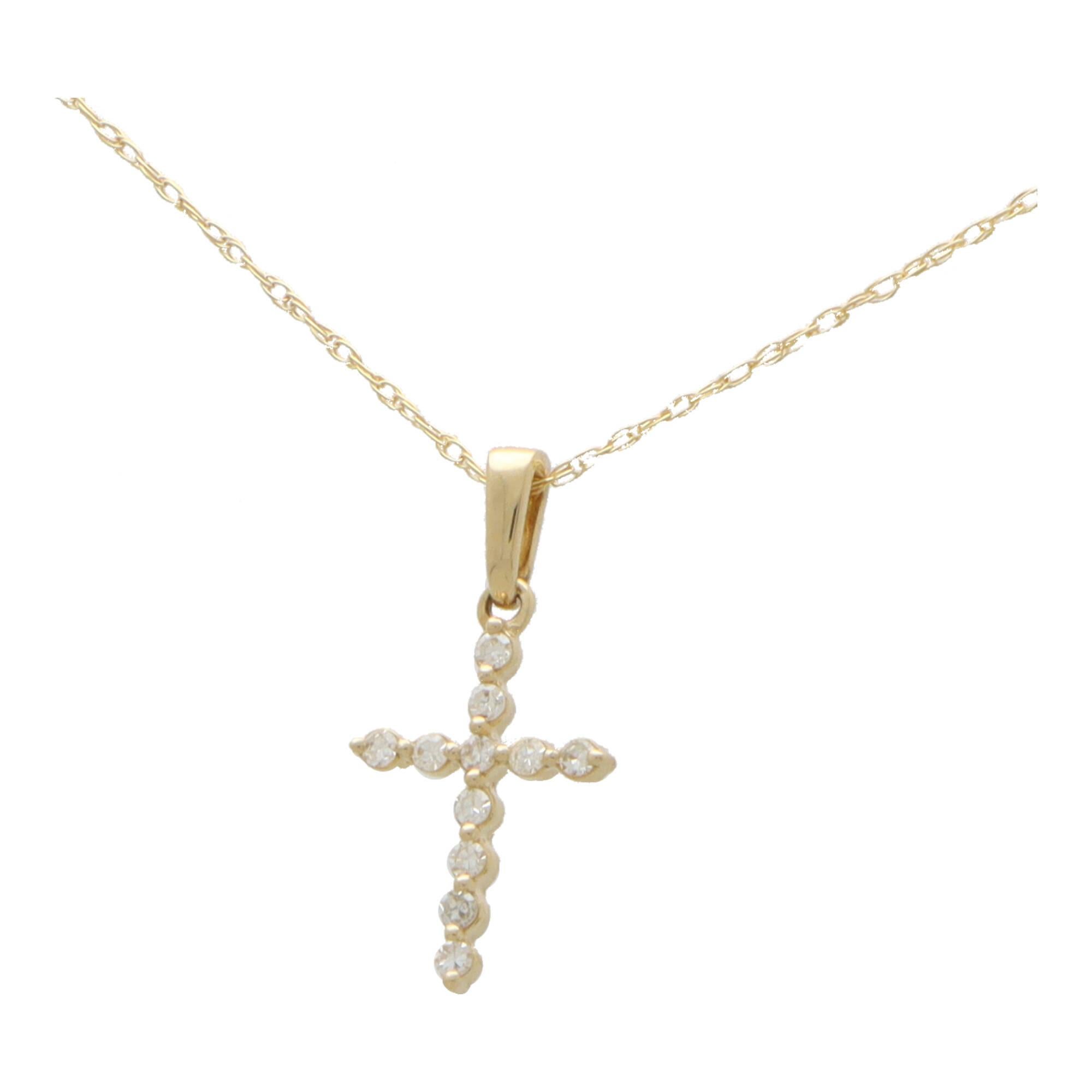  A dainty diamond cross pendant necklace set in 14k yellow gold.

The pendant depicts a cross motif and is claw set with exactly 11 round brilliant cut diamonds. The cross hangs from a yellow gold bail and hangs from a fine 18-inch yellow gold trace