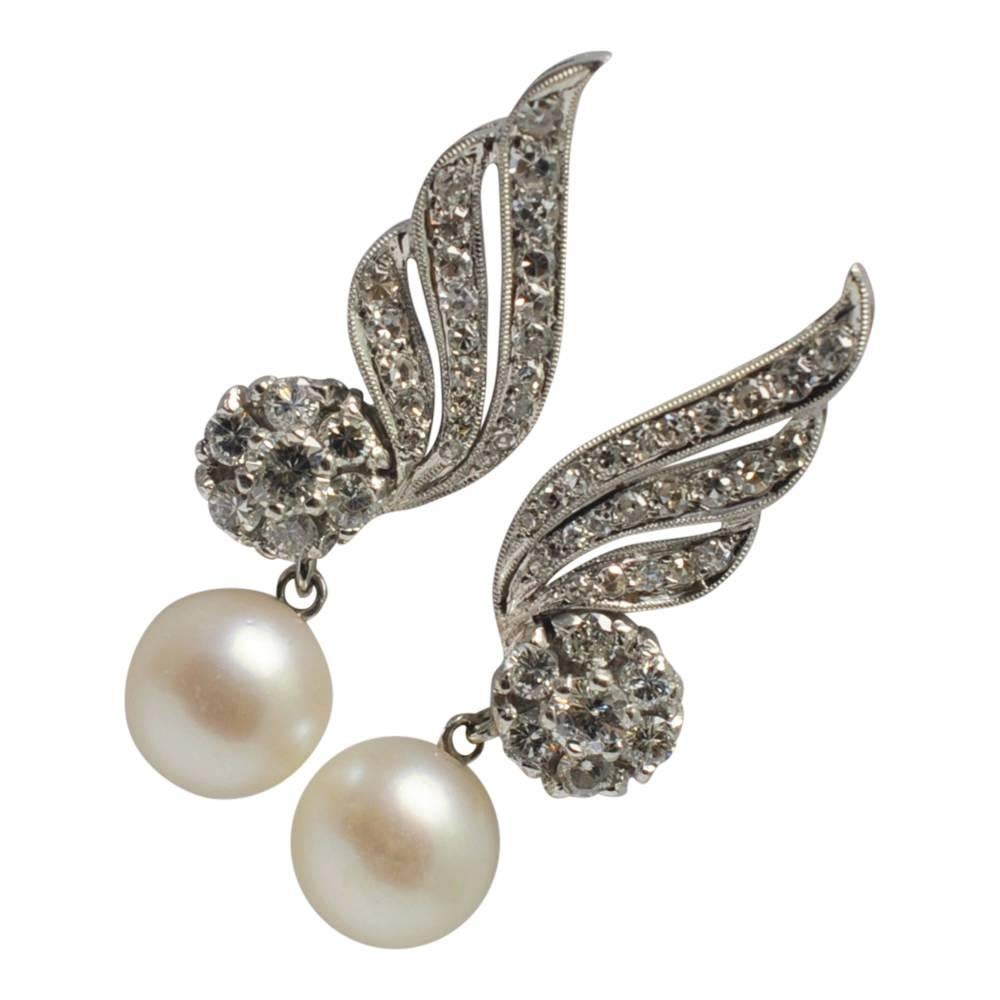 Beautiful vintage cultured pearl and diamond earrings in 18ct white gold;  these are formed of waves and clusters of brilliant and 8-cut diamonds totalling 2cts, below which,  lustrous, creamy 9mm cultured pearls are  suspended.  Length 3.5cm