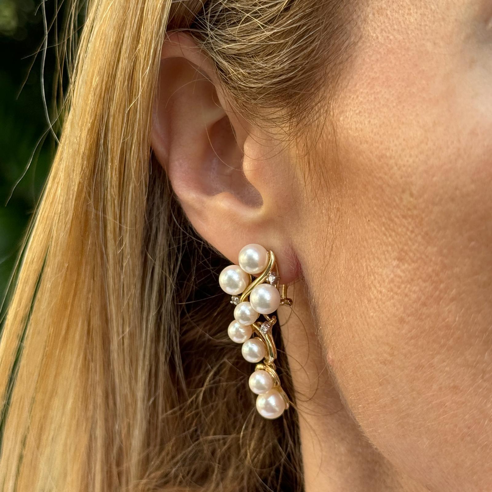 Ohrringe mit Zuchtperlen und Diamanten aus 14 Karat Gelbgold. Die Ohrringe sind mit 6,5 mm großen weißen Perlen und 6 runden Diamanten im Brillantschliff mit einem Gesamtgewicht von ca. 0,10 Karat besetzt. Die Ohrringe sind 1.5 cm lang. Gewicht: