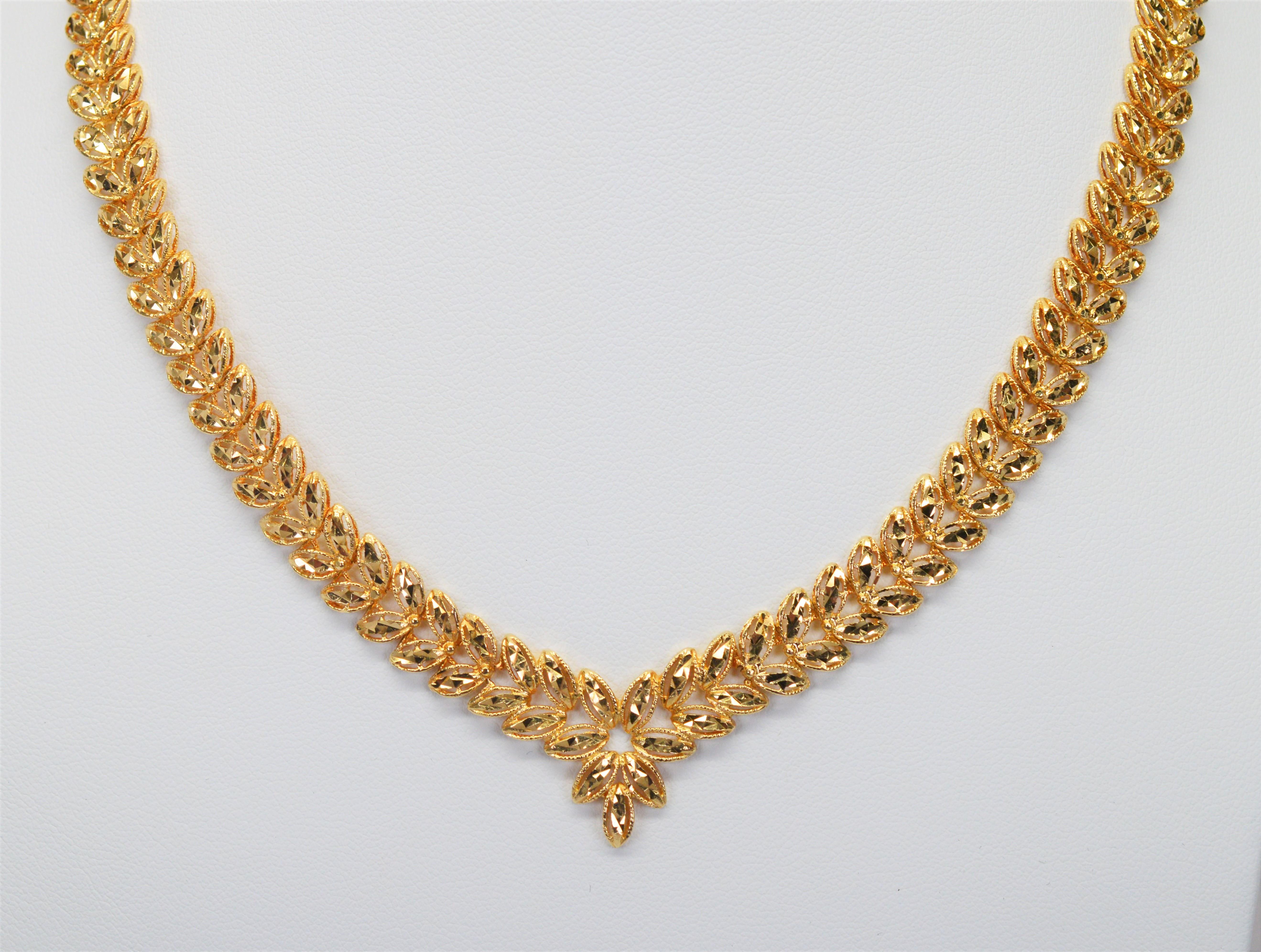 Elegant at the collar, in stunning diamond-cut fourteen 14 karat yellow gold, the open work filigree of this fine necklace defines the botanical inspired leaf design of this statement piece. At 16-1/2 inch in length and 3/8 inch wide the piece is