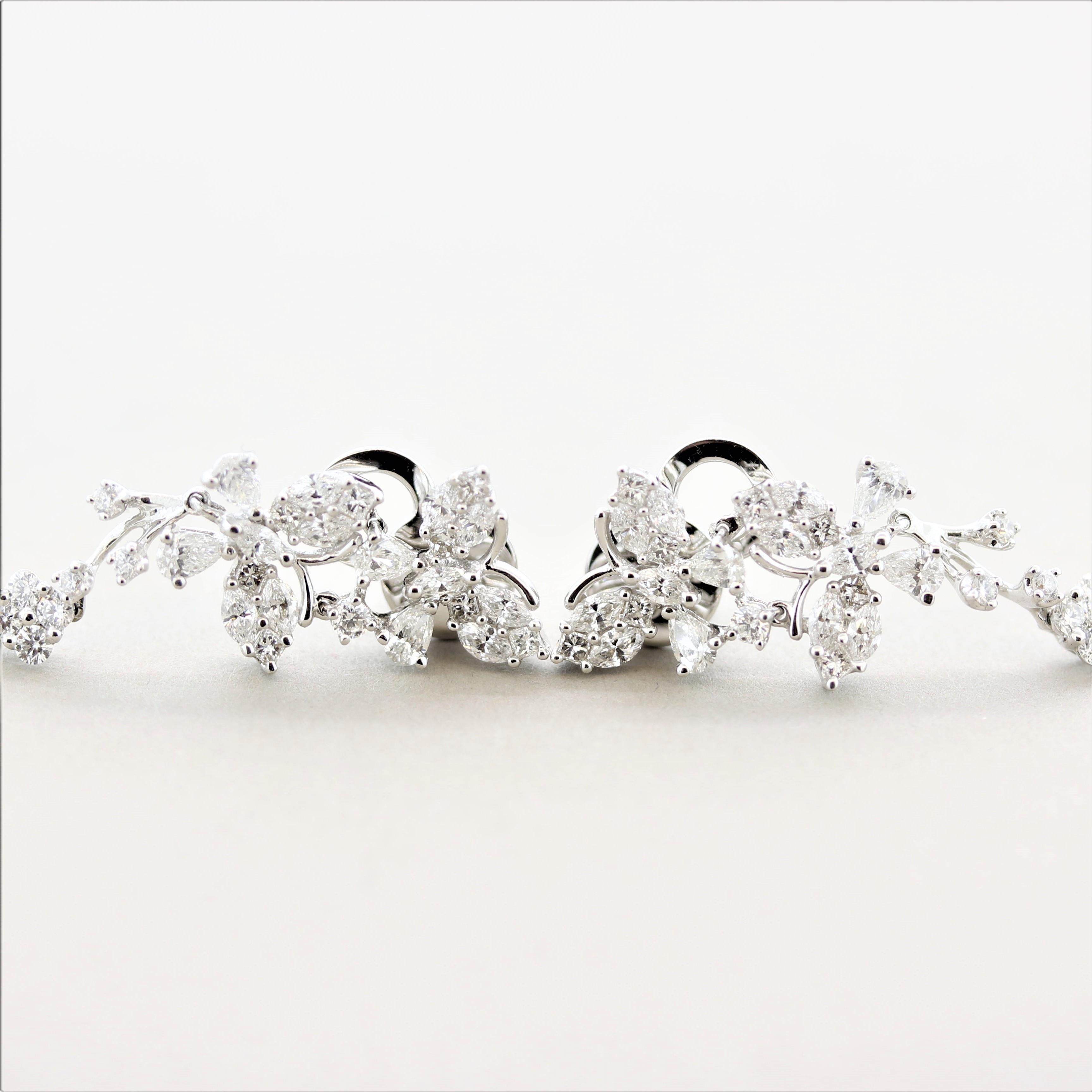 A unique pair of long dangle earrings featuring 3.31 carats of round brilliant-cut and pear-shaped diamonds set in floral designs and butterfly outlines. It appears as two diamond studded butterflies are flying up leaving a trail of diamond flowers