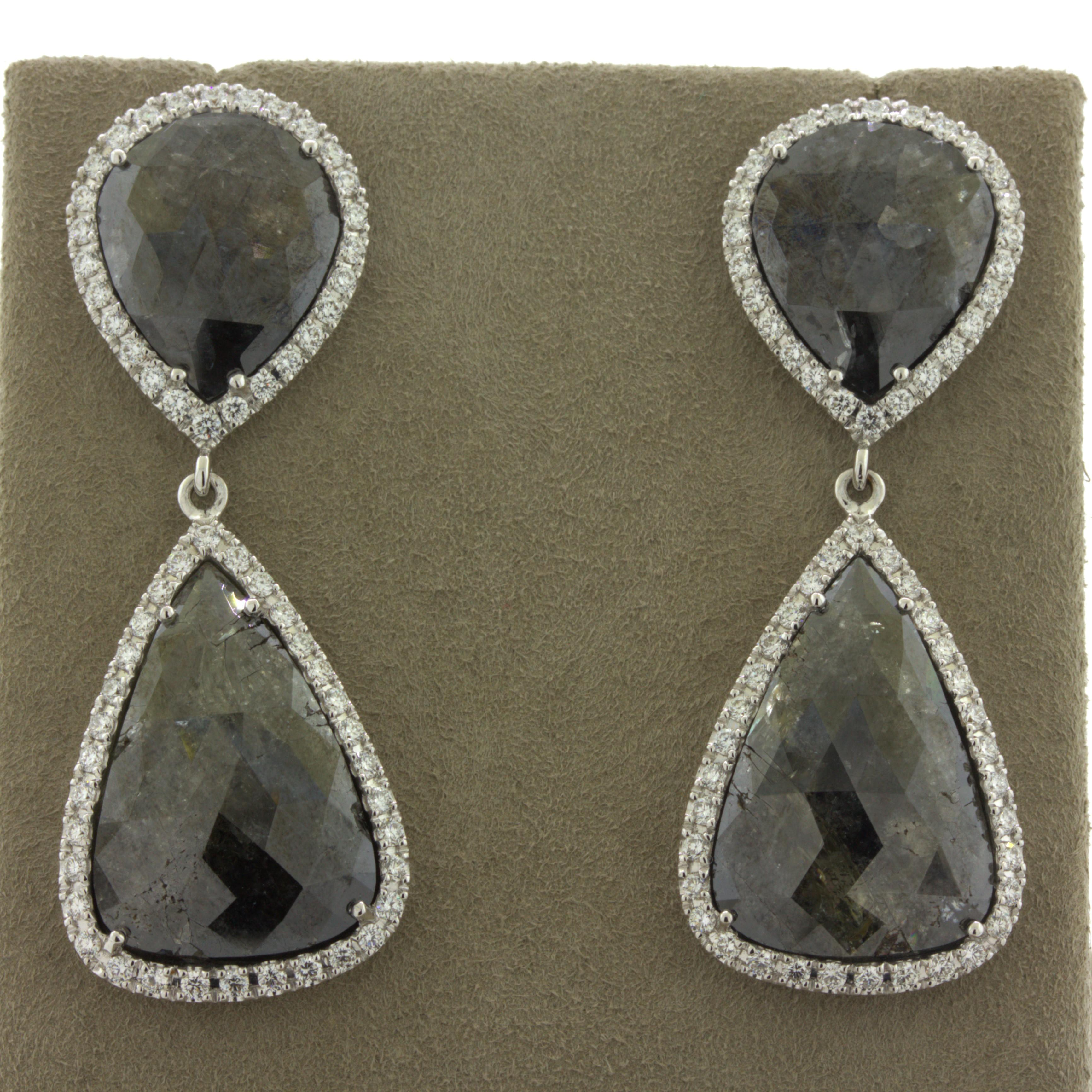 A lovely and substantial pair of diamond drop earrings featuring 4 large diamond slices weighing 30.35 carats! They are large slices of diamonds with a rose-cut finish on their tops to add brilliance to the stones. They are complemented by halos of