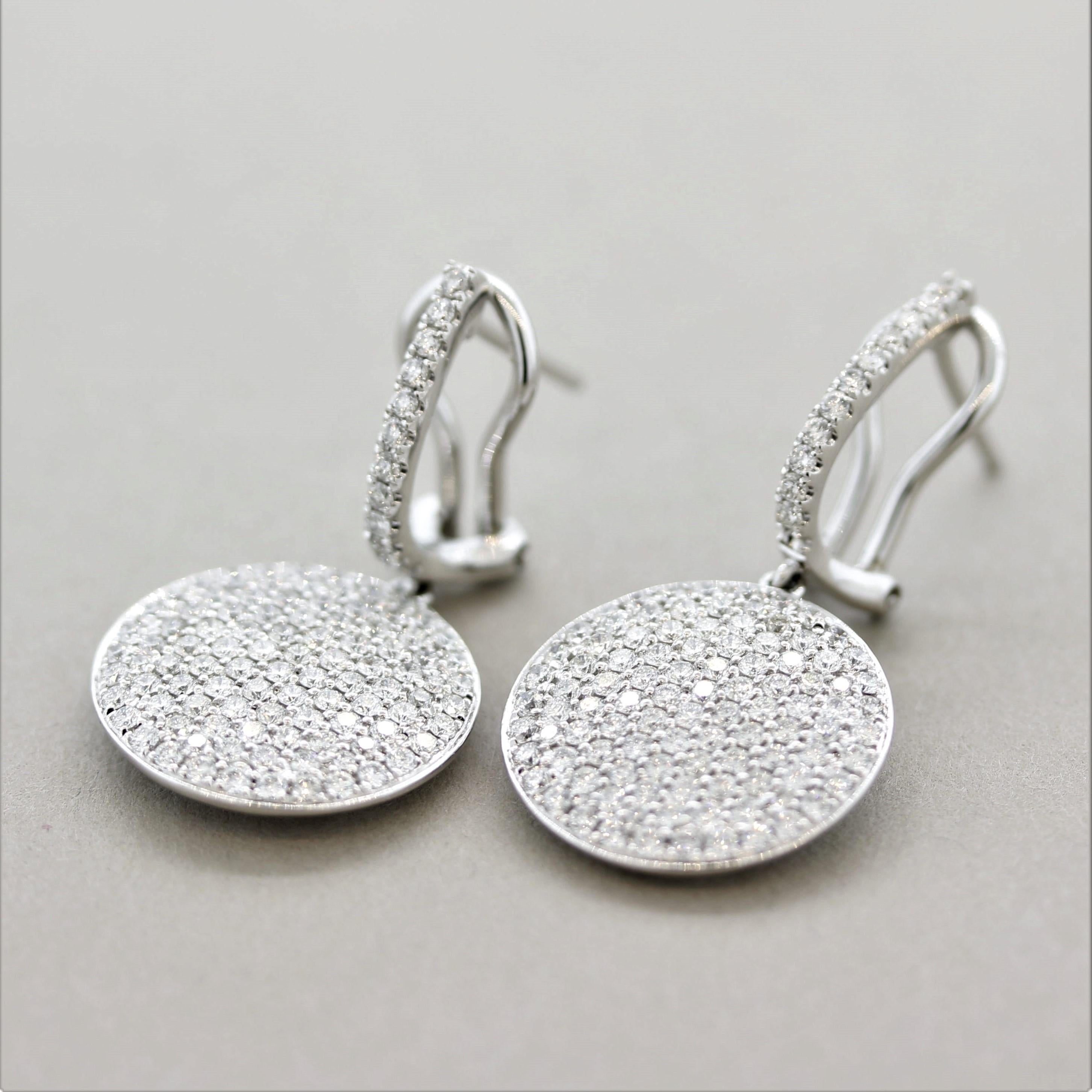 A lovely pair of drop earrings! They feature 1.93 carats of fine round brilliant-cut diamonds which are pave set over gold drop disks. The diamond studded disks drop and dangle from the earrings allowing the light to hit all angles of the stones.
