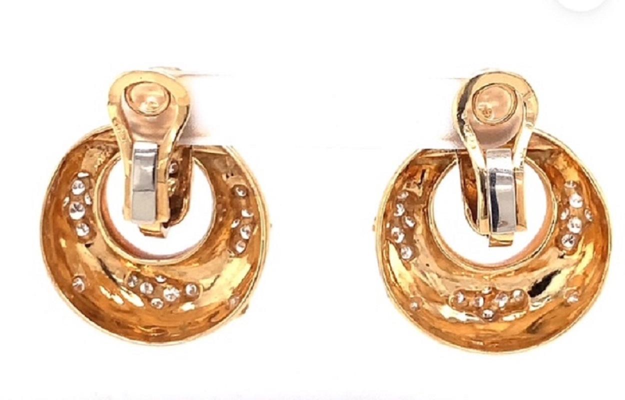 This dazzling pair of 18K yellow gold diamond doorknocker-style earclips from the 1970s blends playful design with timeless elegance. The circular motif is adorned with 48 round brilliant cut diamonds totaling 1.72 carats, with G-H color and VS-1