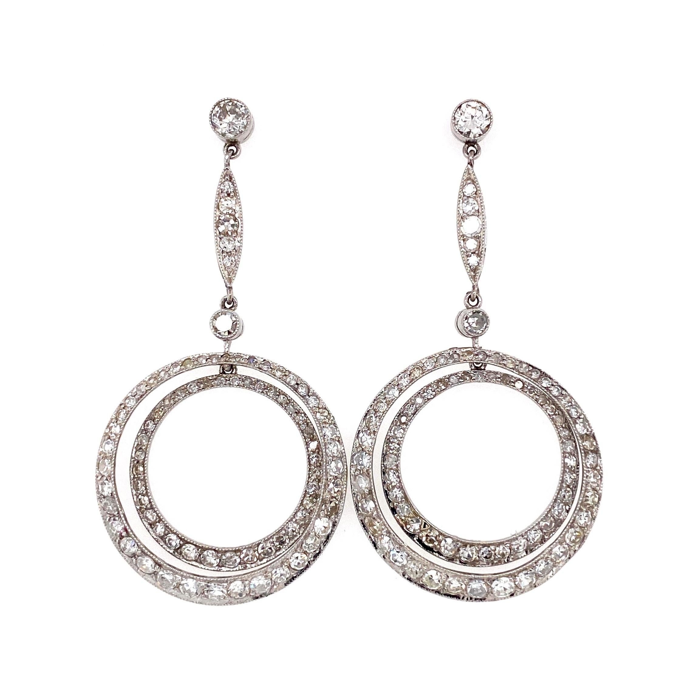 Simply Beautiful! Finely Detailed Art Deco Revival Double Circle Diamond Drop Earrings. Hand crafted in Platinum and Hand set with round diamonds, approx. 4.50tcw. Earrings measuring approx. 2” l x 1” w. The earrings are in excellent condition and