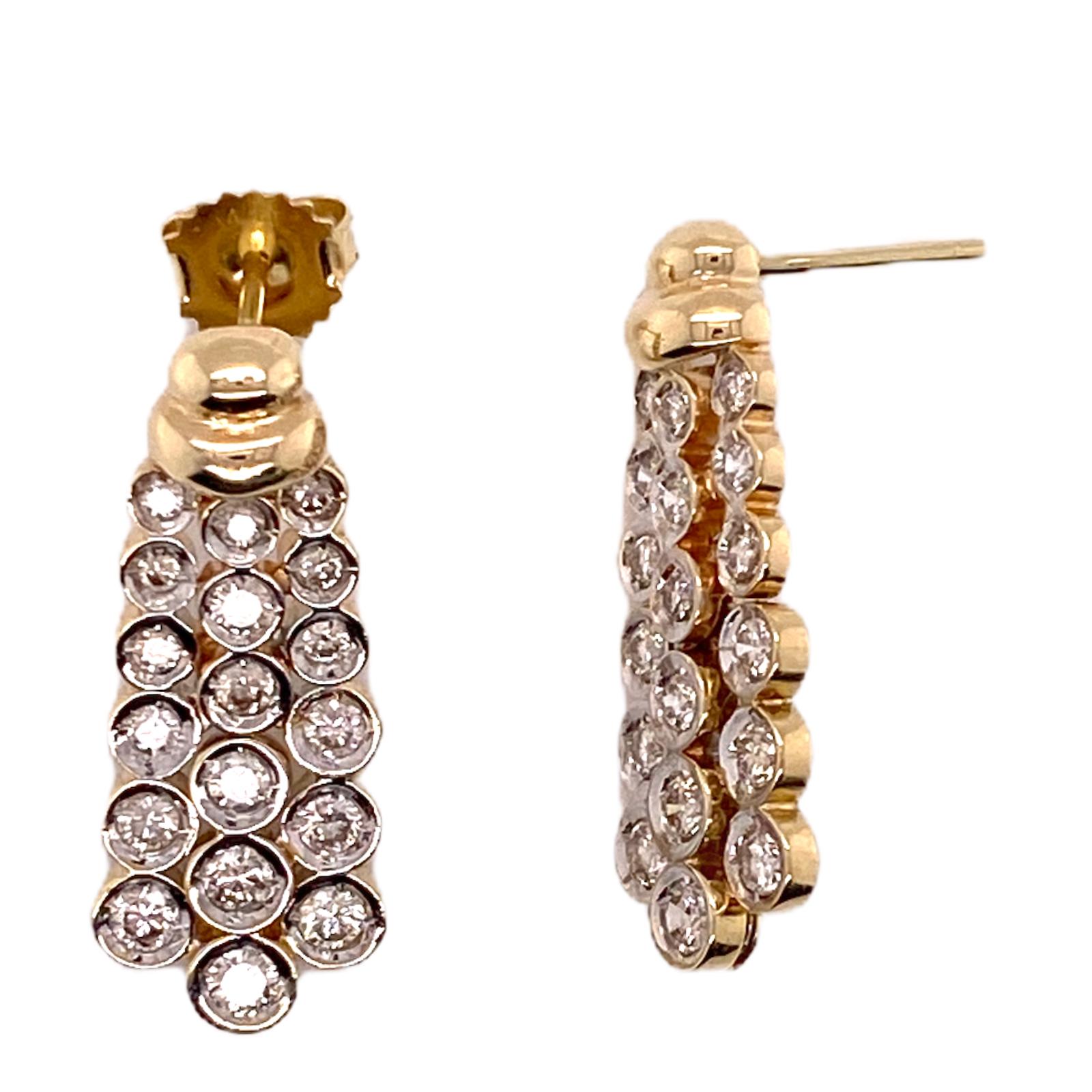 Beautiful bezel set diamond drop earrings fashioned in 14 karat white and yellow gold. The 36 bezel set round brilliant cut diamonds weigh approximately 1.50 carat total weight, and are graded H-I color and SI clarity. The earrings measure 1.2