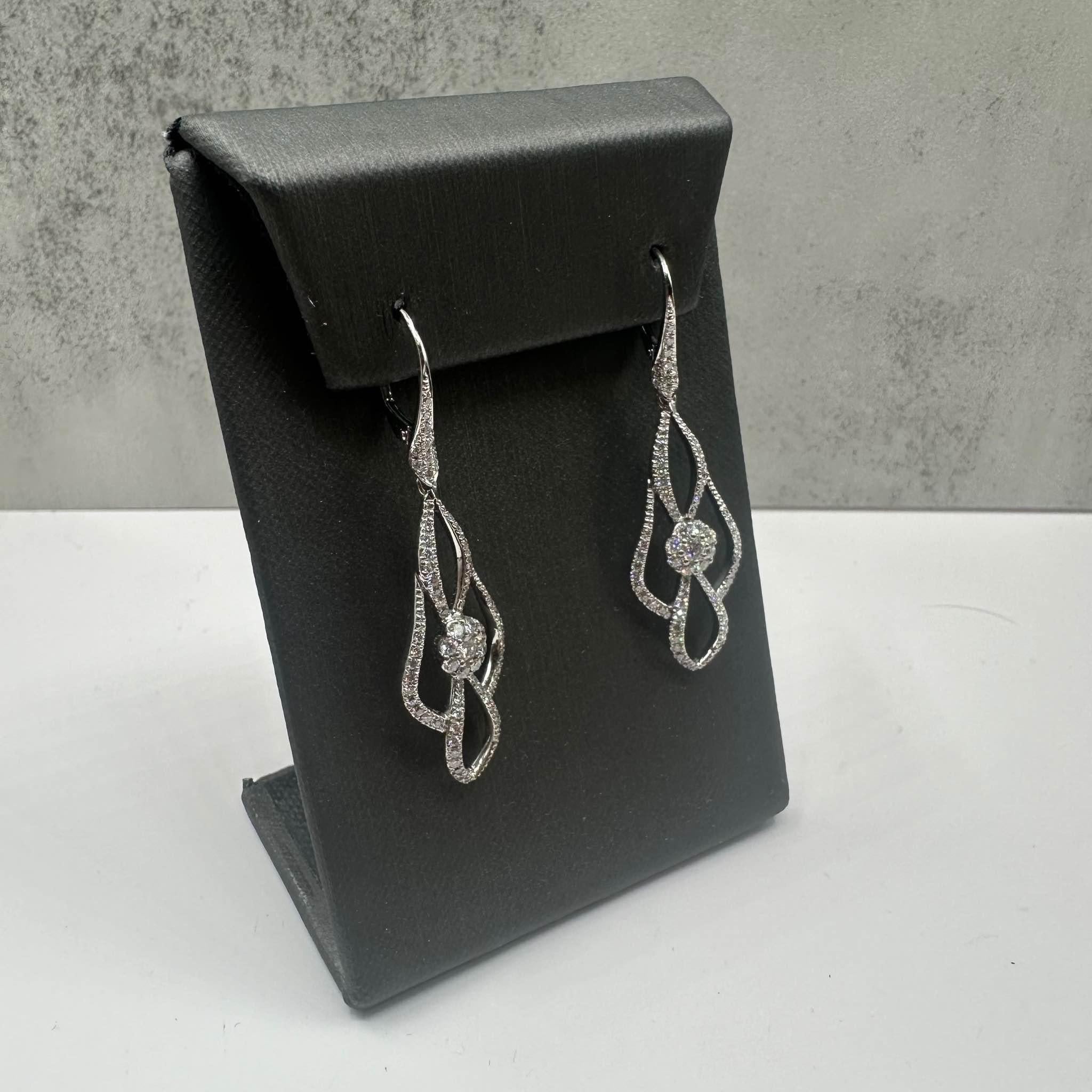 These stunning Diamond Drop Earrings in 18kt white gold feature approximately 1.2ctw of natural GH VS/SI round diamonds, offering brilliant sparkle with every movement. Weighing 6.5 grams, these earrings provide a substantial yet comfortable feel.