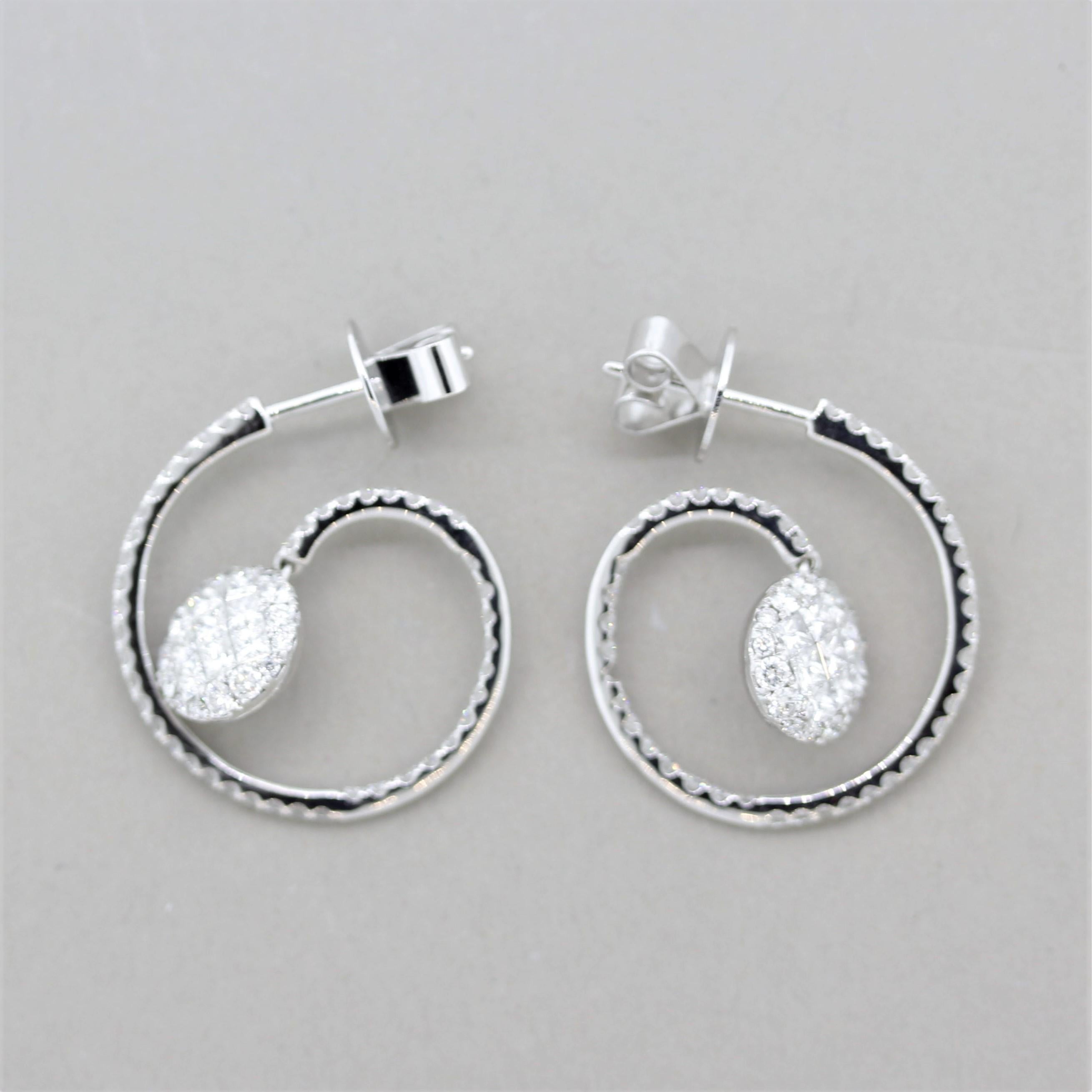 A unique, stylish, and fine pair of diamond earrings! They feature round brilliant-cut diamonds set on the spiral portion of the earrings as well as princess-cut diamonds which are invisibly-set on the round drop portion in the center of the