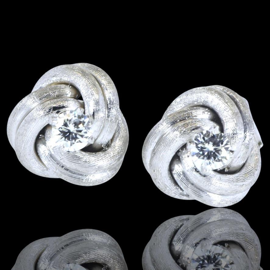 Diamond earrings, in the form of a cunning diamond love knot. These earrings are perfect in a twisted white gold knot centering a fine prong set white brilliant cut diamond. Each diamond is estimated to weigh, by our internal gemologist, .25 cts.