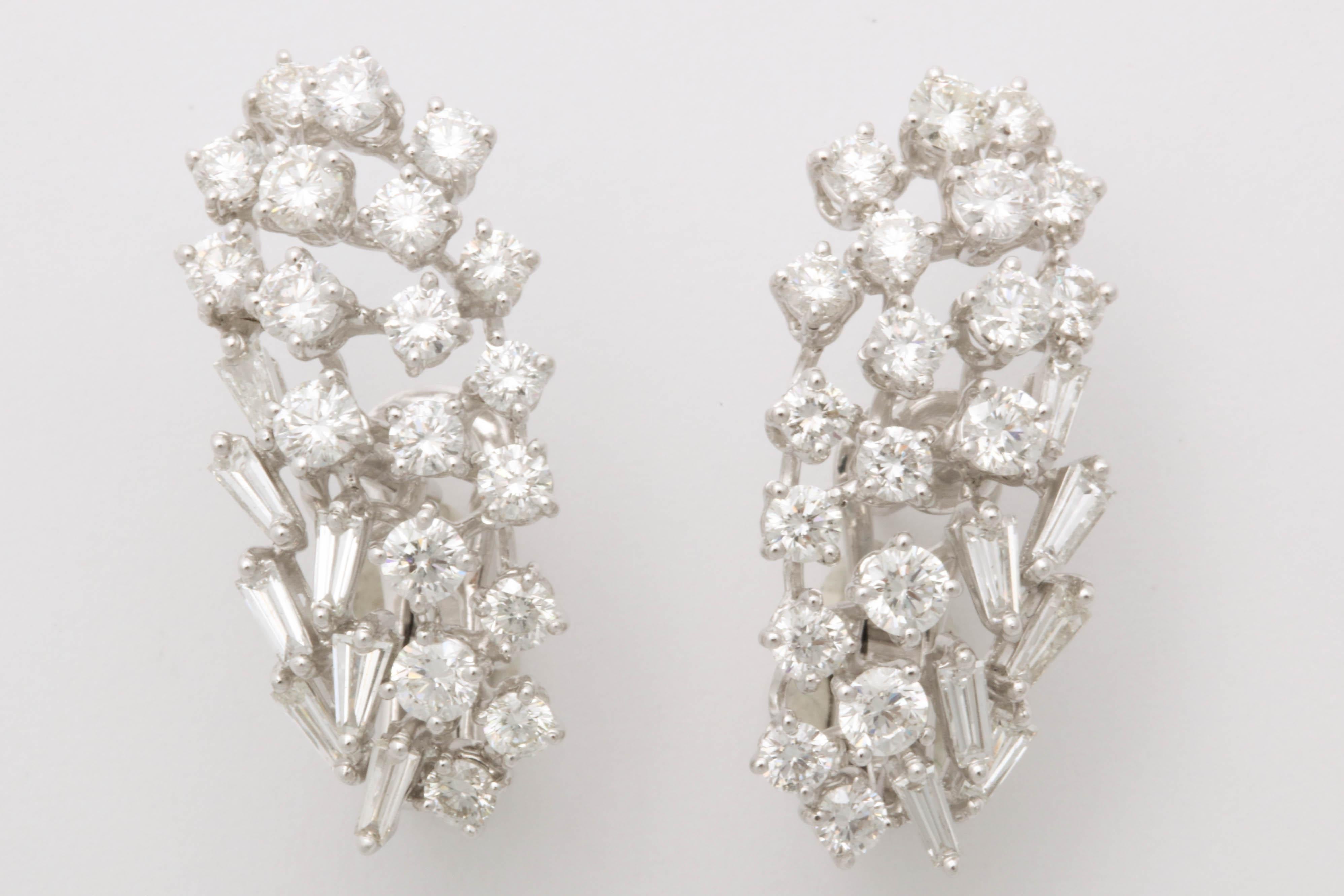 
Ein einzigartiges Design aus weißen runden Brillanten und Diamanten im Baguetteschliff, gefasst in 18 Karat Weißgold. 

Diese Ohrringe sind so konzipiert, dass sie am Ohr 