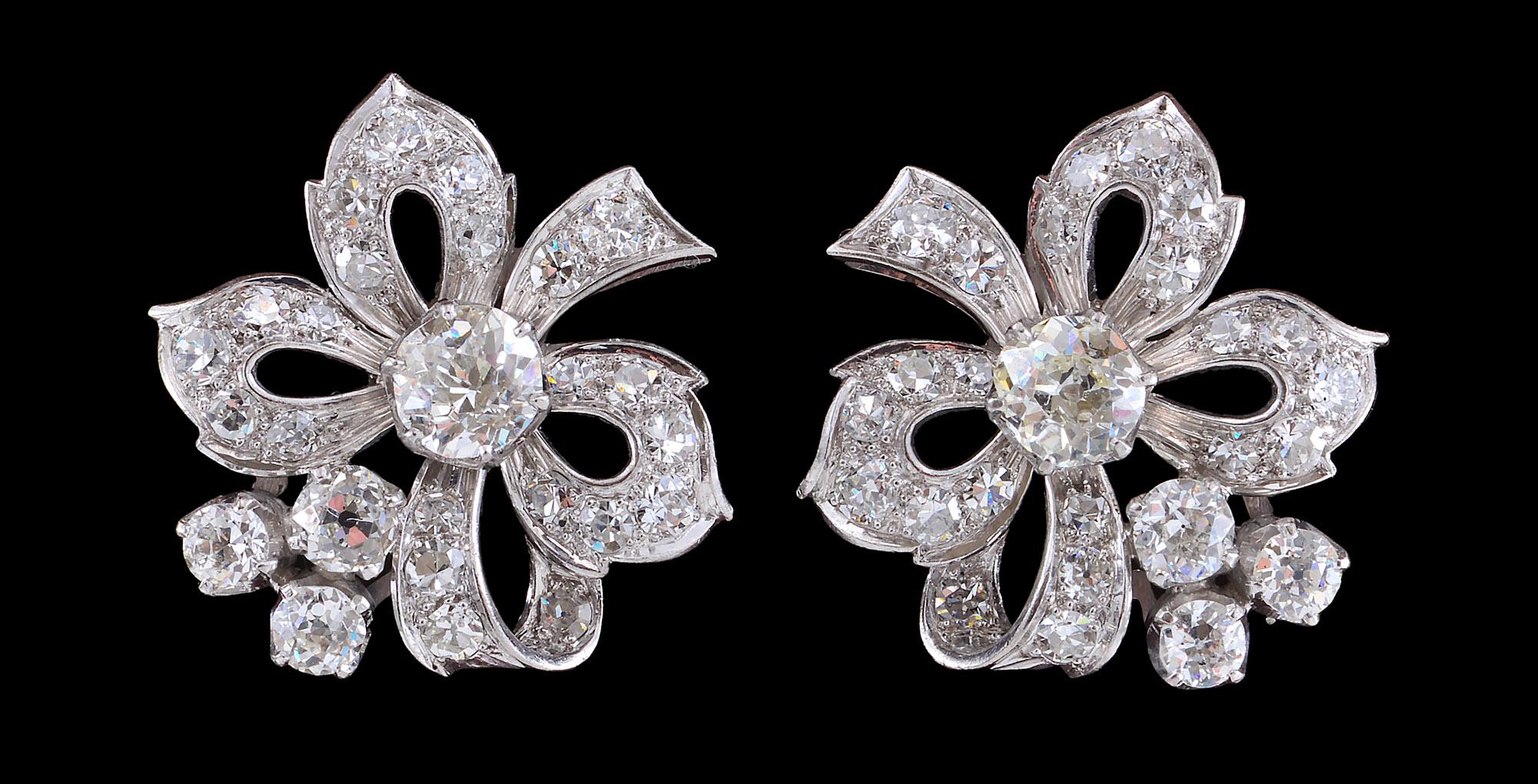 These exuberant and fun Diamond earrings of the 1950s stylised as bows  are each is set with a central diamond of an estimated weight of 0.66 cts surrounded with a mixture of the old and single stone diamonds. The stones are set in both claw and