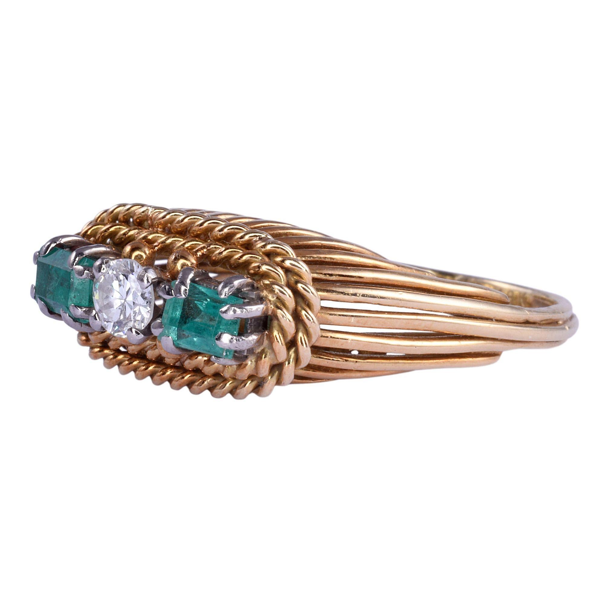 Vintage diamond emerald 18K gold ring. This vintage ring is crafted in 18 karat yellow gold featuring a twisted rope design with a .15 carat diamond center. The diamond has VS2 clarity and G color. There are also two emeralds at .40 carat total