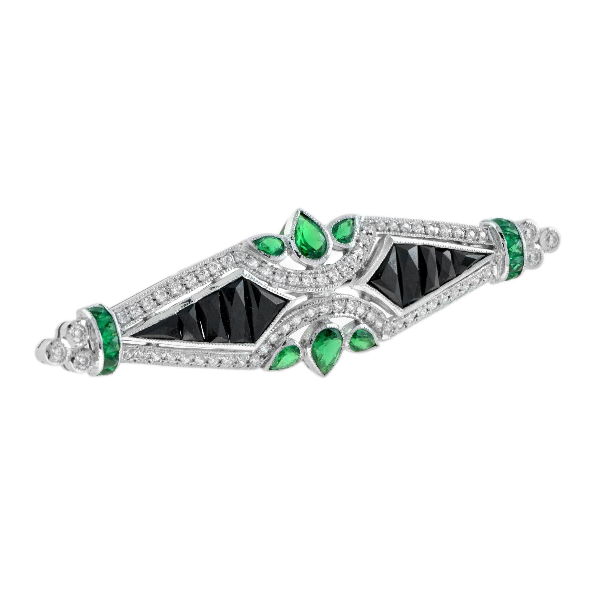 A marvelous design of symmetry along with accents of vibrant color make this Art Deco inspired brooch, masterfully hand in 14k white gold. Frosted with shimmering diamonds, on each side features French cut onyx and emeralds. Green emerald leaves are