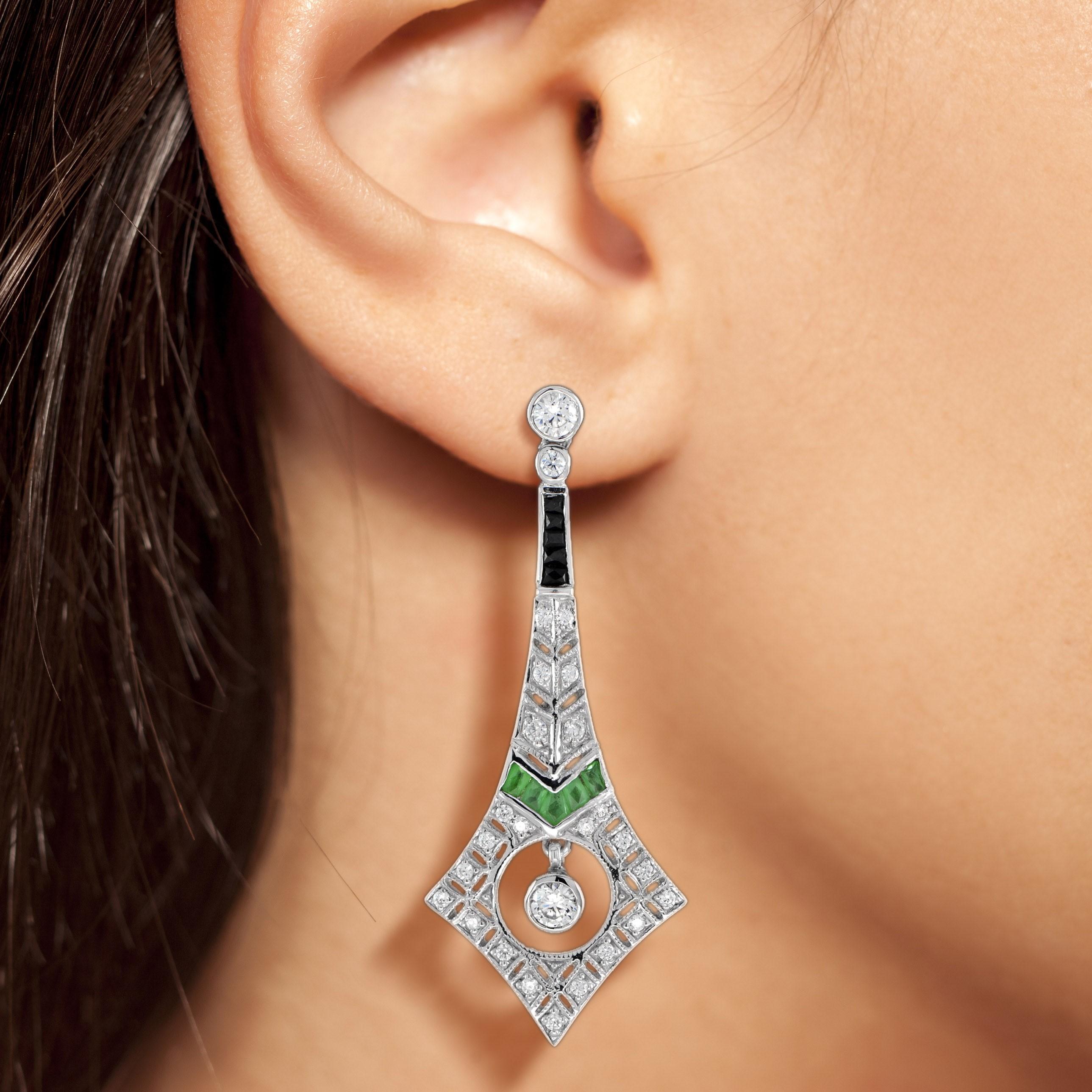 These Art Deco inspired diamond emerald and onyx drop earrings in 18k white gold are a luxurious decadence to be enjoyed for years to come. Each earrings is adorned with a total of four-teen French cut emeralds, five onyxes and sparkling diamonds,